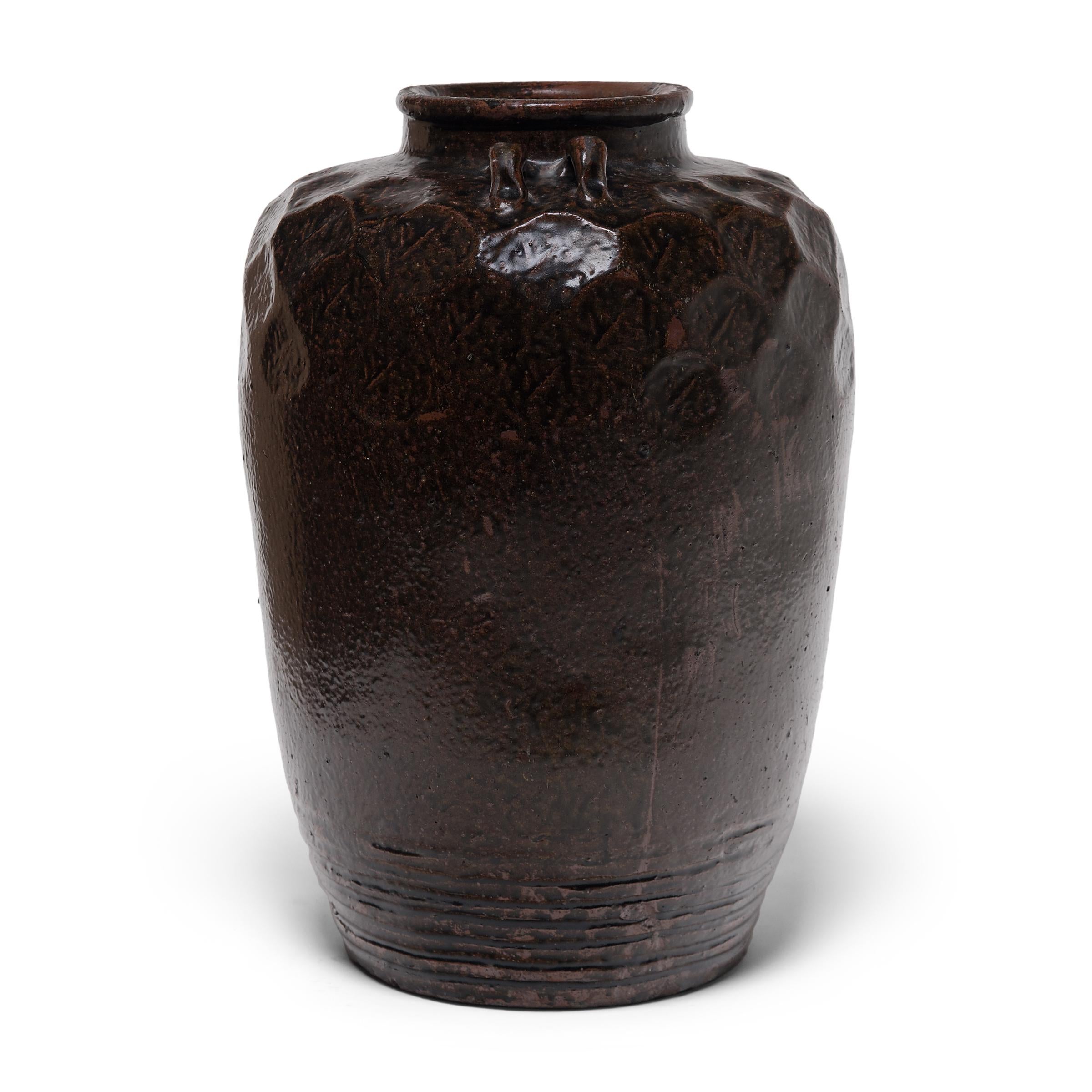 In Qing-dynasty China, large glazed jars such as this were used to store wines, foods, and other consumable items. The combination of high shoulders textured by an irregular, faceted surface and the subtle ridged texture along the sides gives the