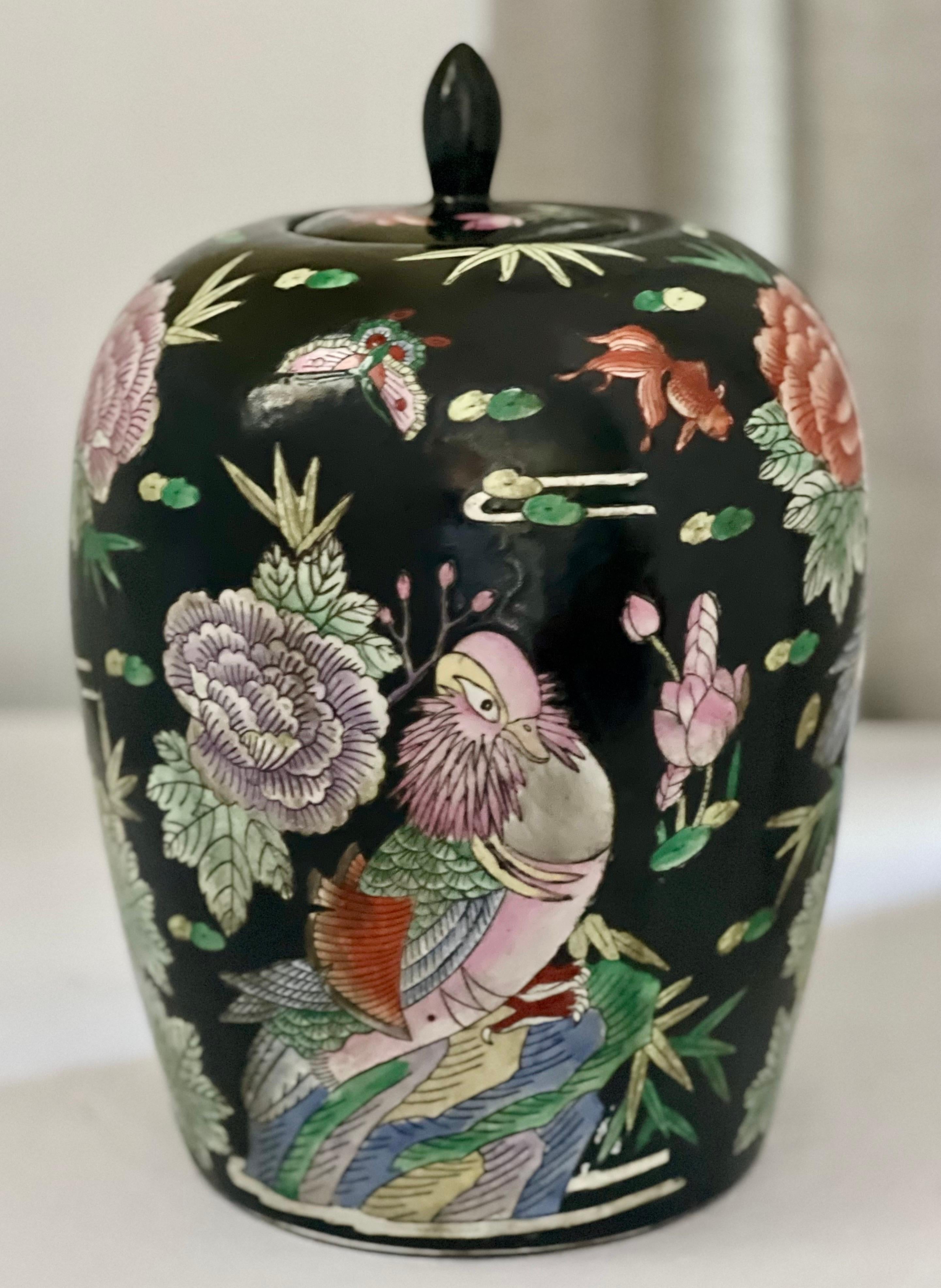 Early 20th century Chinese Famille Noire porcelain ovoid ginger jar with lid.

Wonderful ovoid shape jar with nature themed design hand painted with large birds, flowers, koi fish, lily pads, dragonflies and butterflies. Soft shades of peach, pink,