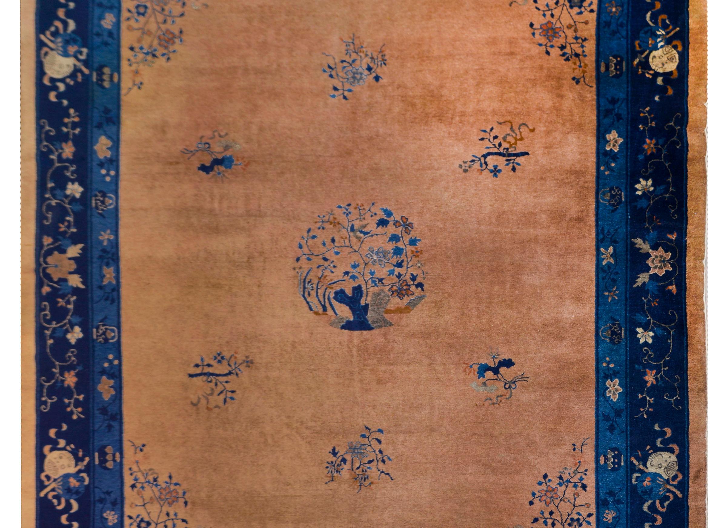 A beautiful early 20th century Chinese Feti rug with a large central floral medallion with flowering trees amidst a field of more flowers, and surrounded by a wide border containing many auspicious Chinese motifs including scrolls of knowledge, and