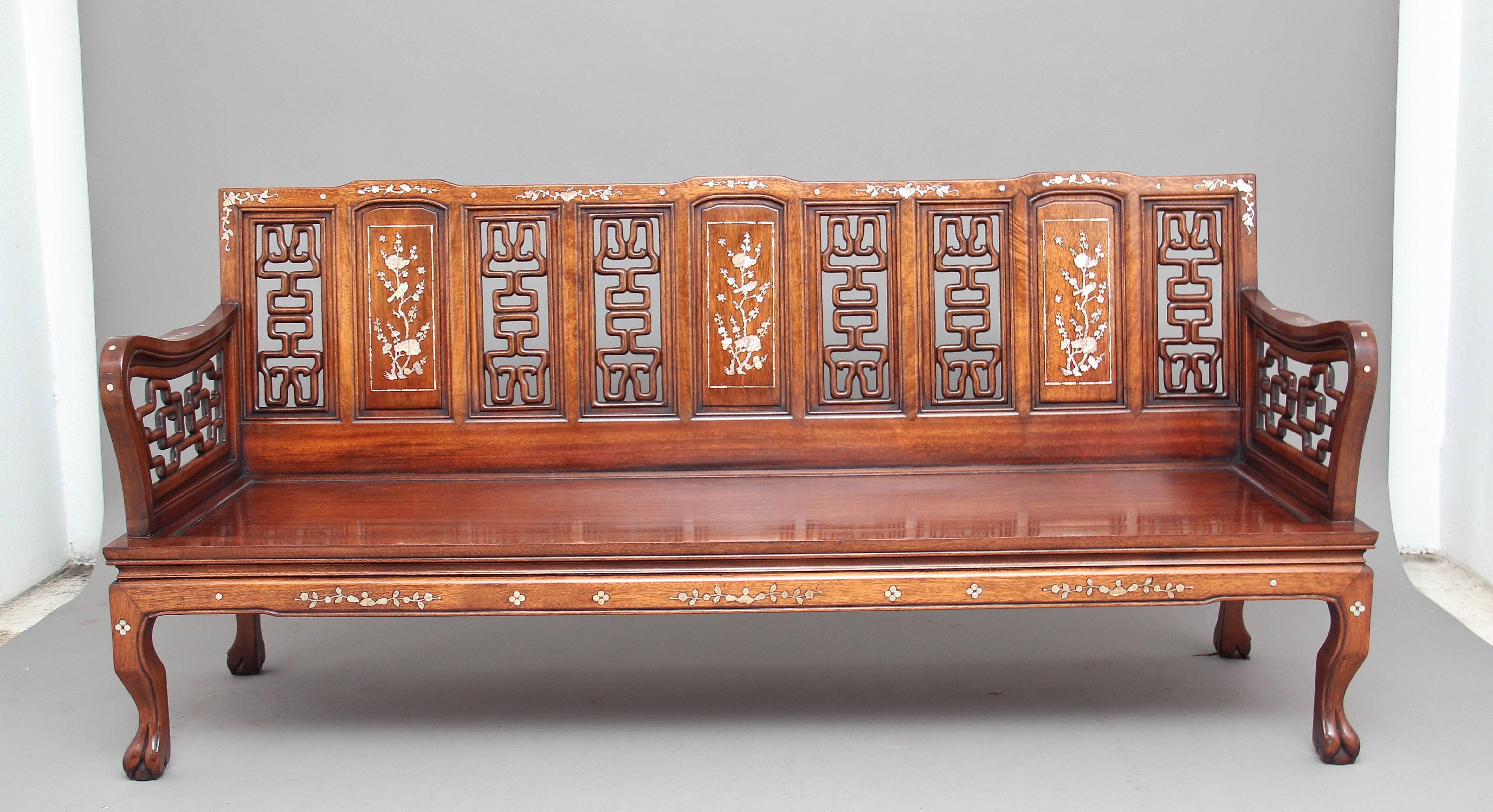Early 20th century Chinese five-piece suite in mahogany inlaid with mother of pearl, comprising of four armchairs and a three seater sofa, the shaped backs having a central panel inlaid with mother of pearl flanked either side with panels decorated