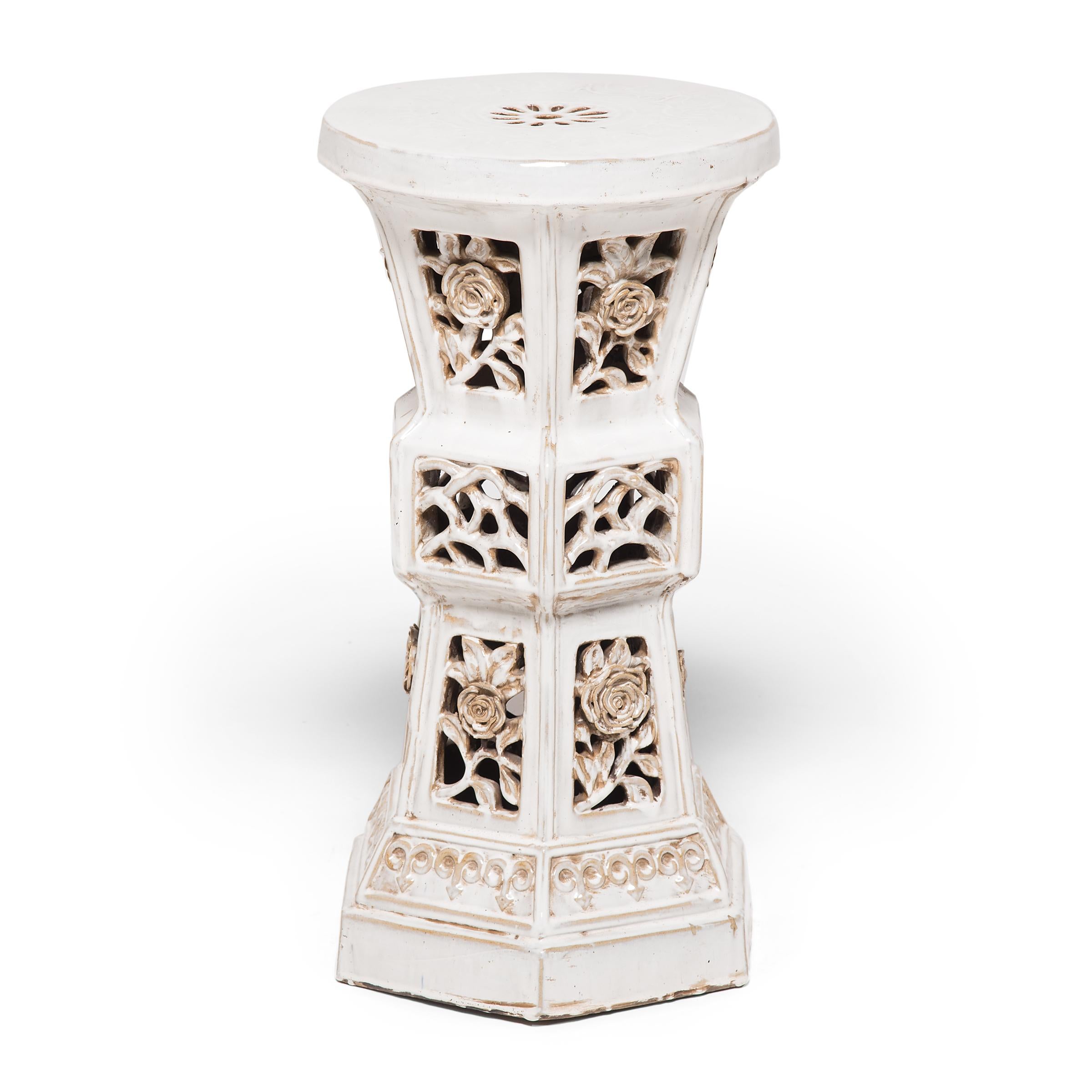 This early 20th century white glazed ceramic pedestal has very unusual form. It was made by an artisan in Southern China and features an hourglass shape and highly dimensional floral cutouts. It was likely used in a garden for incense, tea or plants