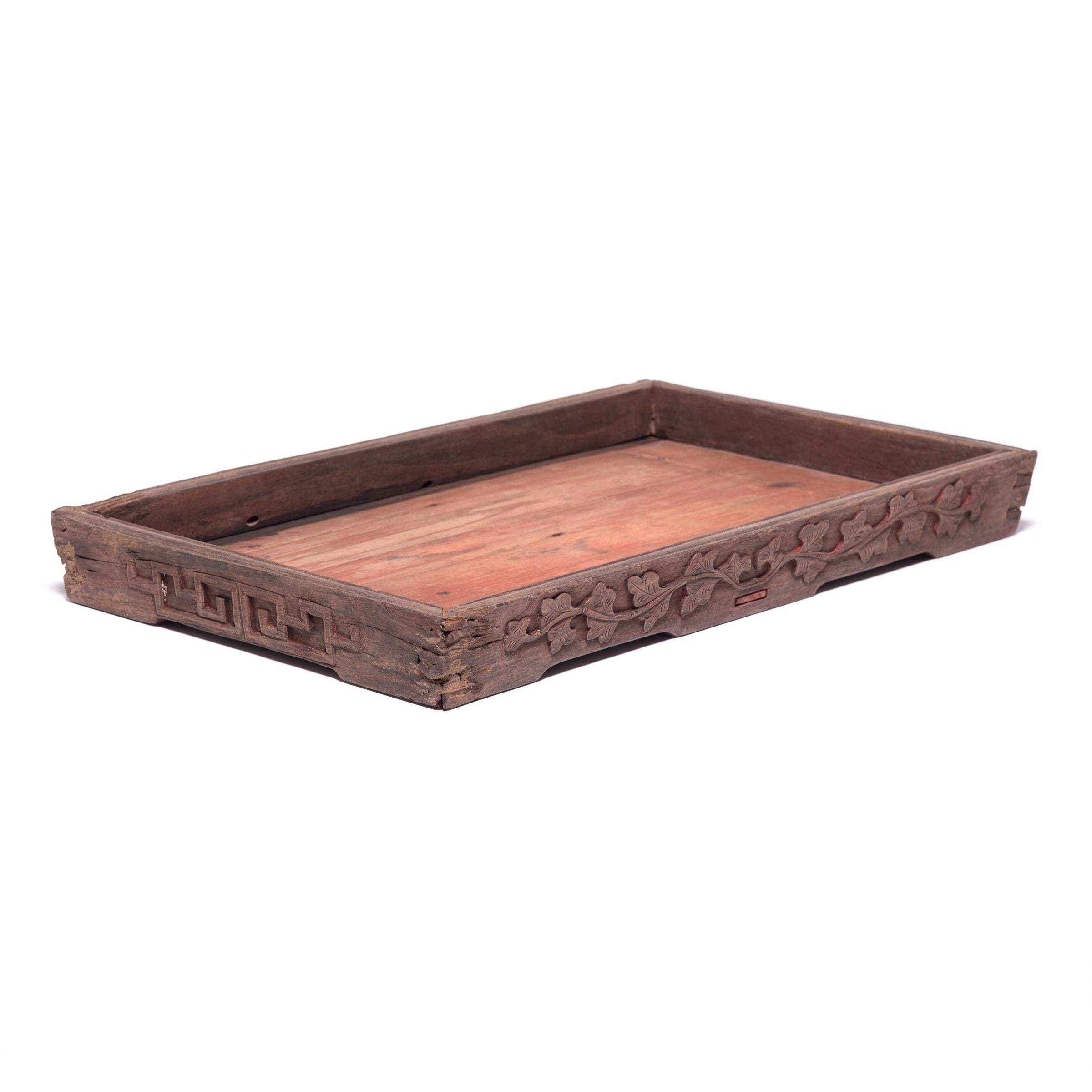 Finely carved floral and geometric motifs and a subtly recessed base give the simple lines of this century-old tray true provincial elegance. It has developed great character from years of serving tea, likely for friends and family gathered on