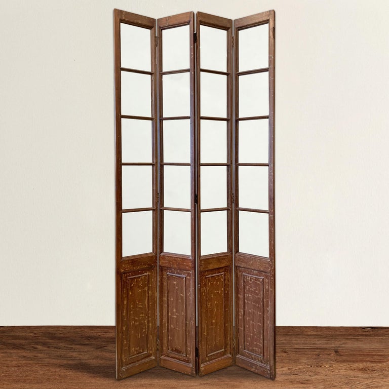 A wonderful early 20th century Chinese four-panel room divider with a striking lacquered finish and each panel containing five glass panes. Perfect for dividing a space or the panels could be retrofitted as closet or pantry doors.