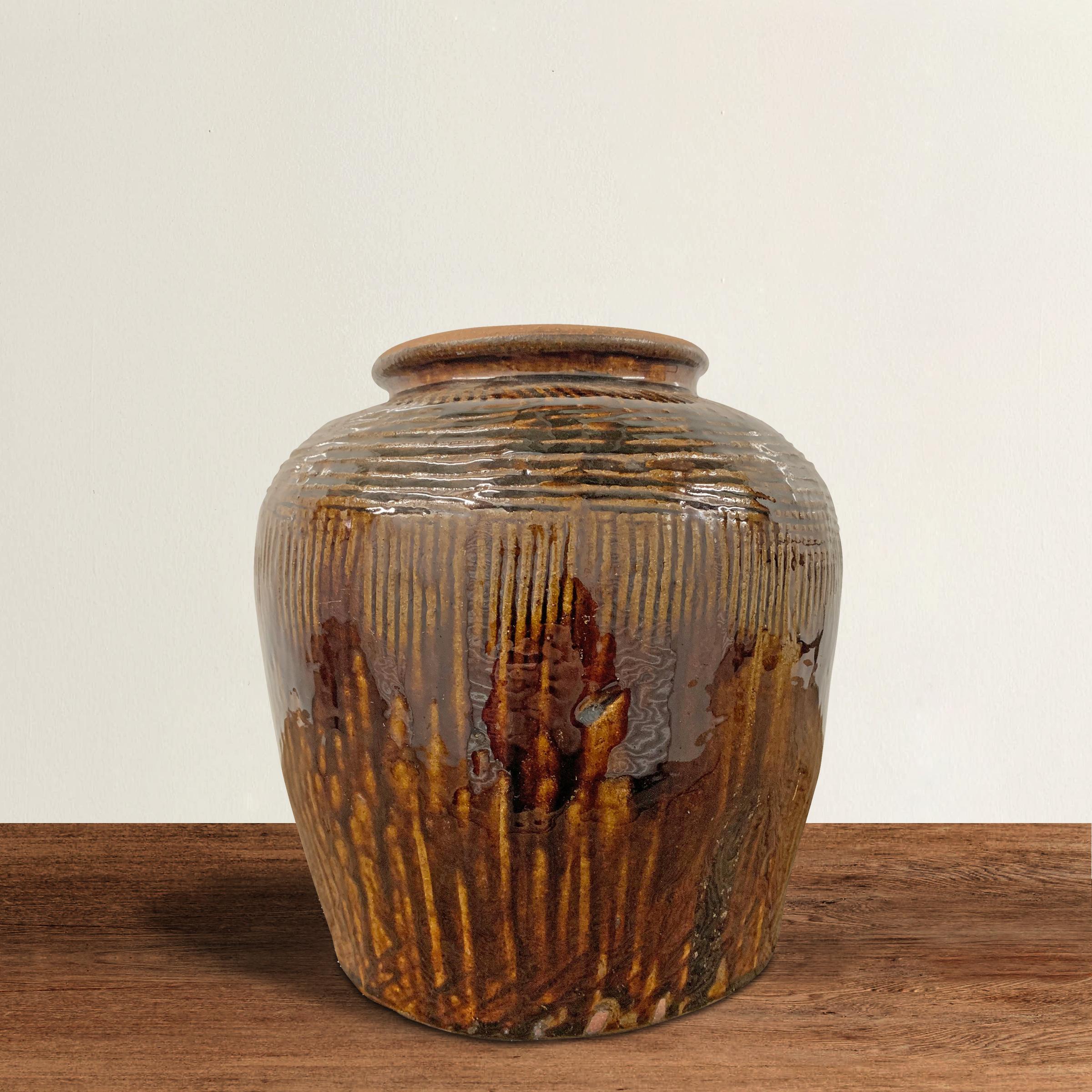 A beautiful early 20th century Chinese brown glazed pot with a raked pattern around the top half of the jar and a drippy glaze pattern around the bottom. Would be an excellent vase for flowers or converted into a table lamp.