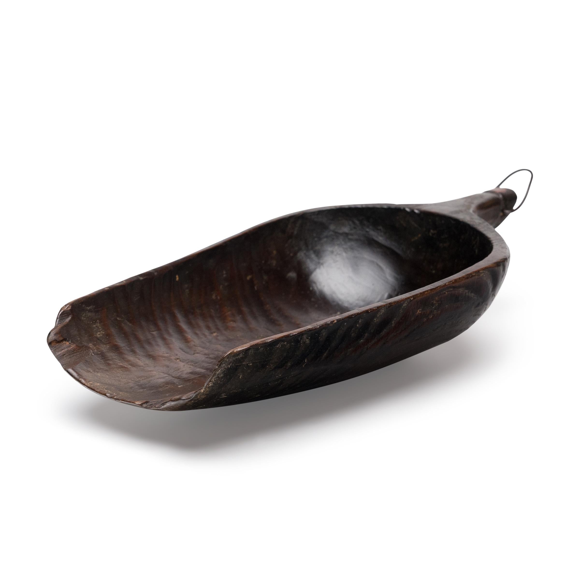 Il y a un siècle, quelqu'un tenait chaque jour dans sa main cette pelle en bois sculpté pour mesurer le riz ou d'autres céréales. Taillée dans un seul bloc de bois, la pelle présente une texture rustique et ciselée ainsi qu'une patine d'usage. Les