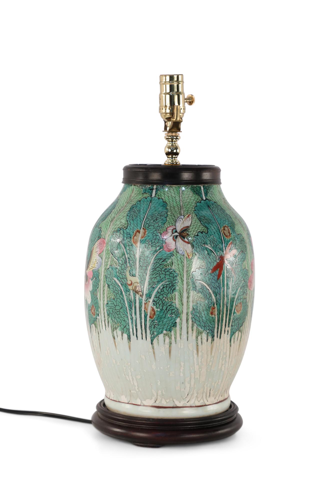 Early 20th century Chinese table lamp made from a vase painted with an intricate green motif of flora and dragon flies and a wooden base.