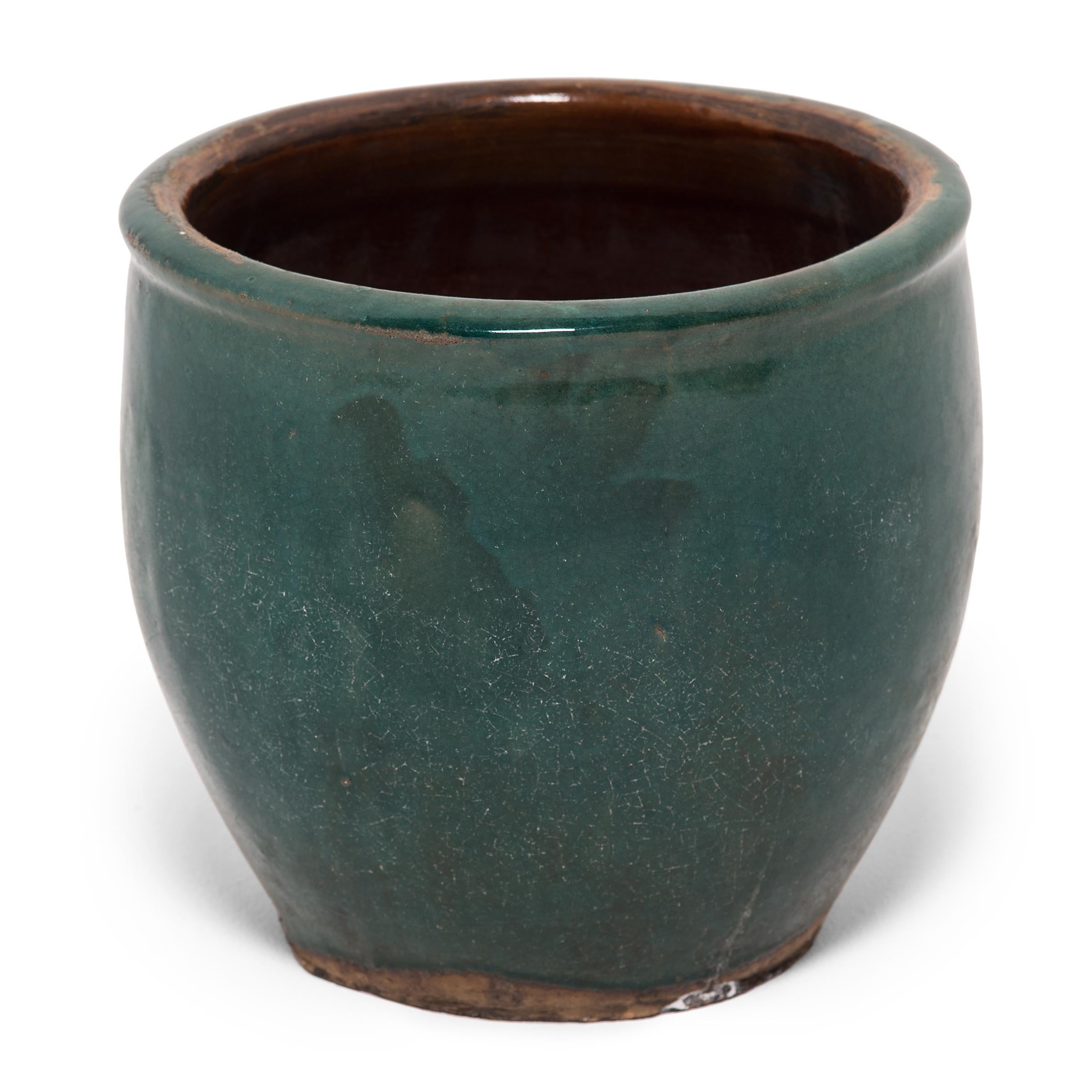 A luminous blue-green glaze sheets, pools, and drips down the surface of this pickling pot, lingering beautifully on every imperfection. Masterfully crafted in the late 19th century, this Qing-dynasty jar once used for household storage exhibits a