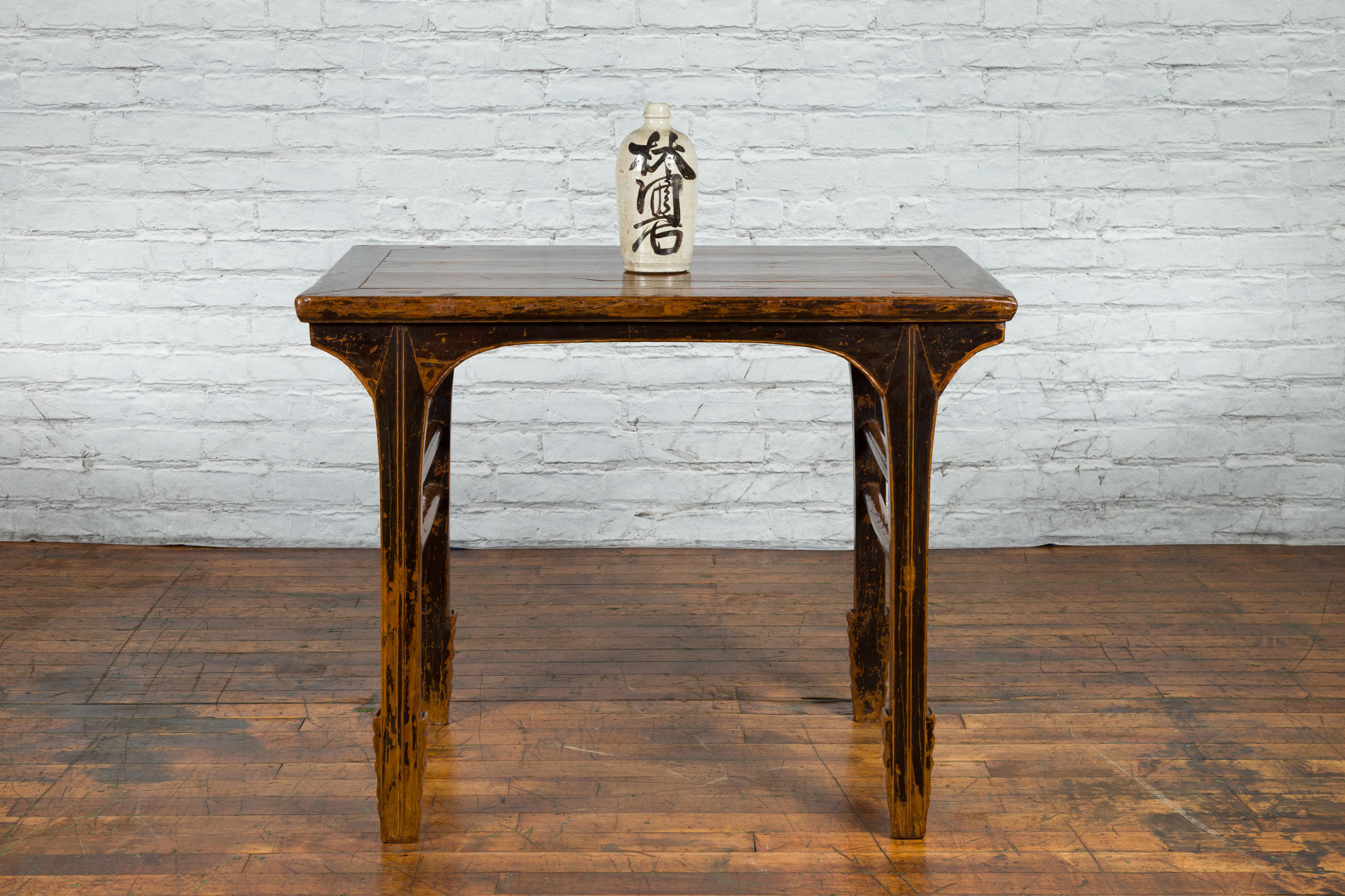 A Chinese hand-carved altar console table from the early 20th century, with distressed patina and double side stretchers. Created in China during the early years of the 20th century, this altar console table features a rectangular top with central