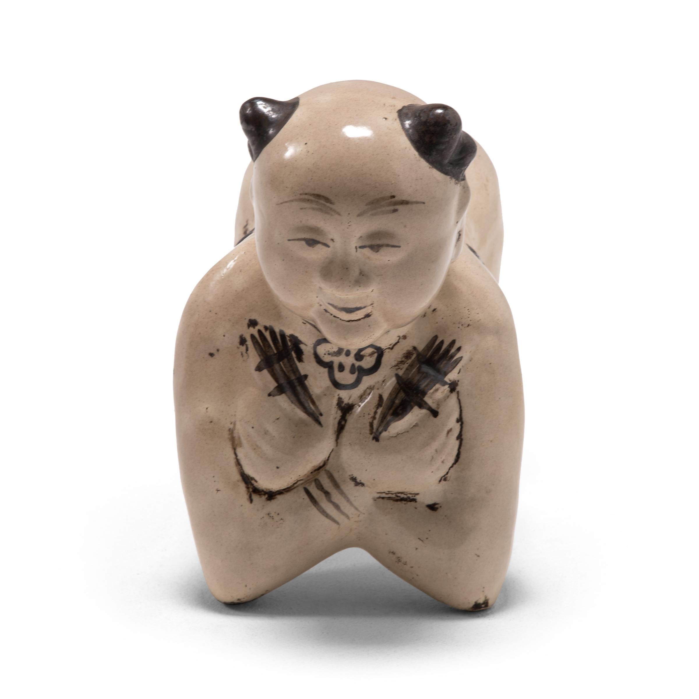 To keep her elaborate hairstyle intact while sleeping, a well-to-do Qing-dynasty woman once used this ceramic headrest as a pillow. This headrest is shaped in the form of a “Ho Ho” boy and would have been used to invoke good fortune. Children were a