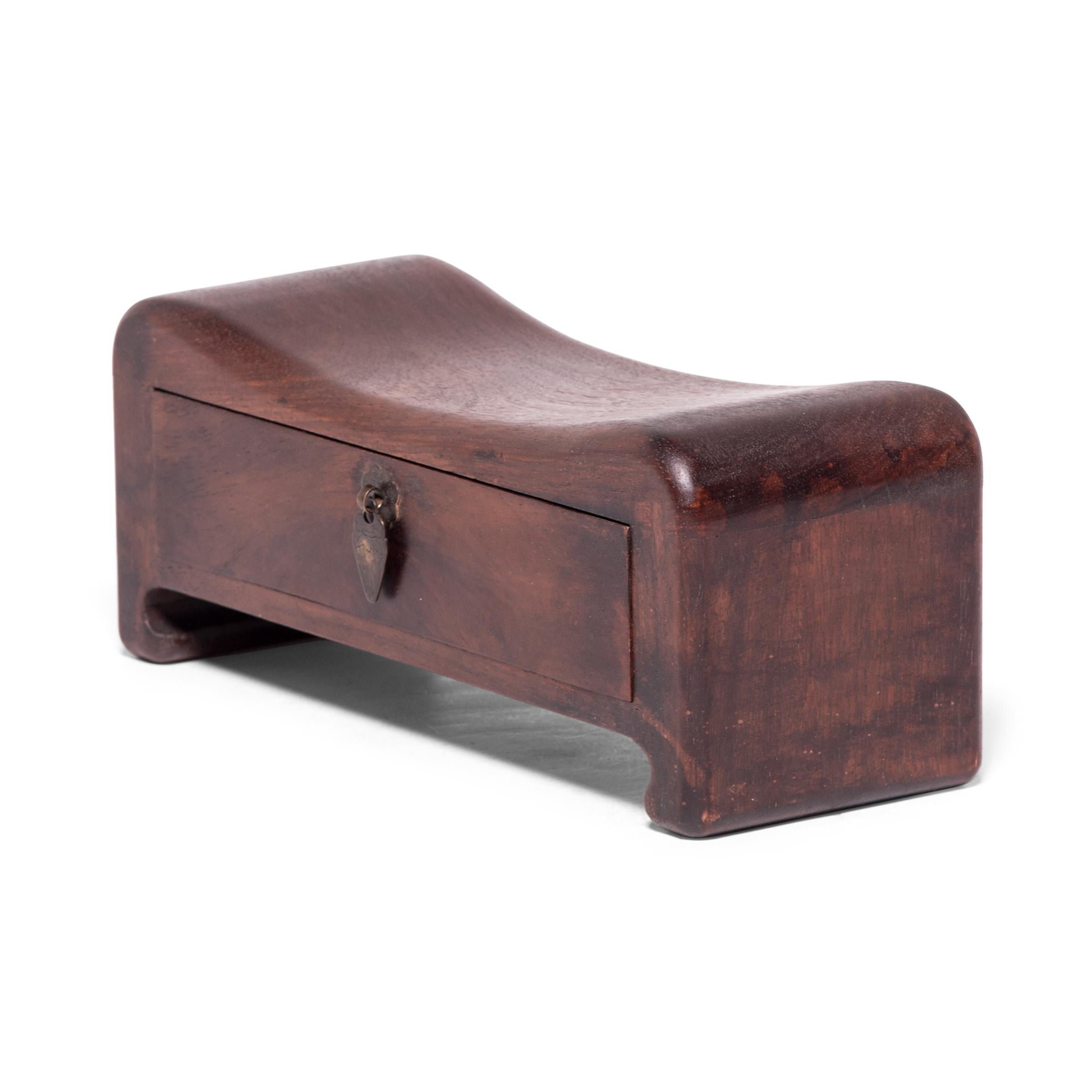 Crafted of a fine hardwood, this early 20th century footed headrest was once used by an upper-class woman in lieu of a pillow. Gently curving to support her head and neck at rest, the headrest also helped to preserve her intricate hairstyle. This
