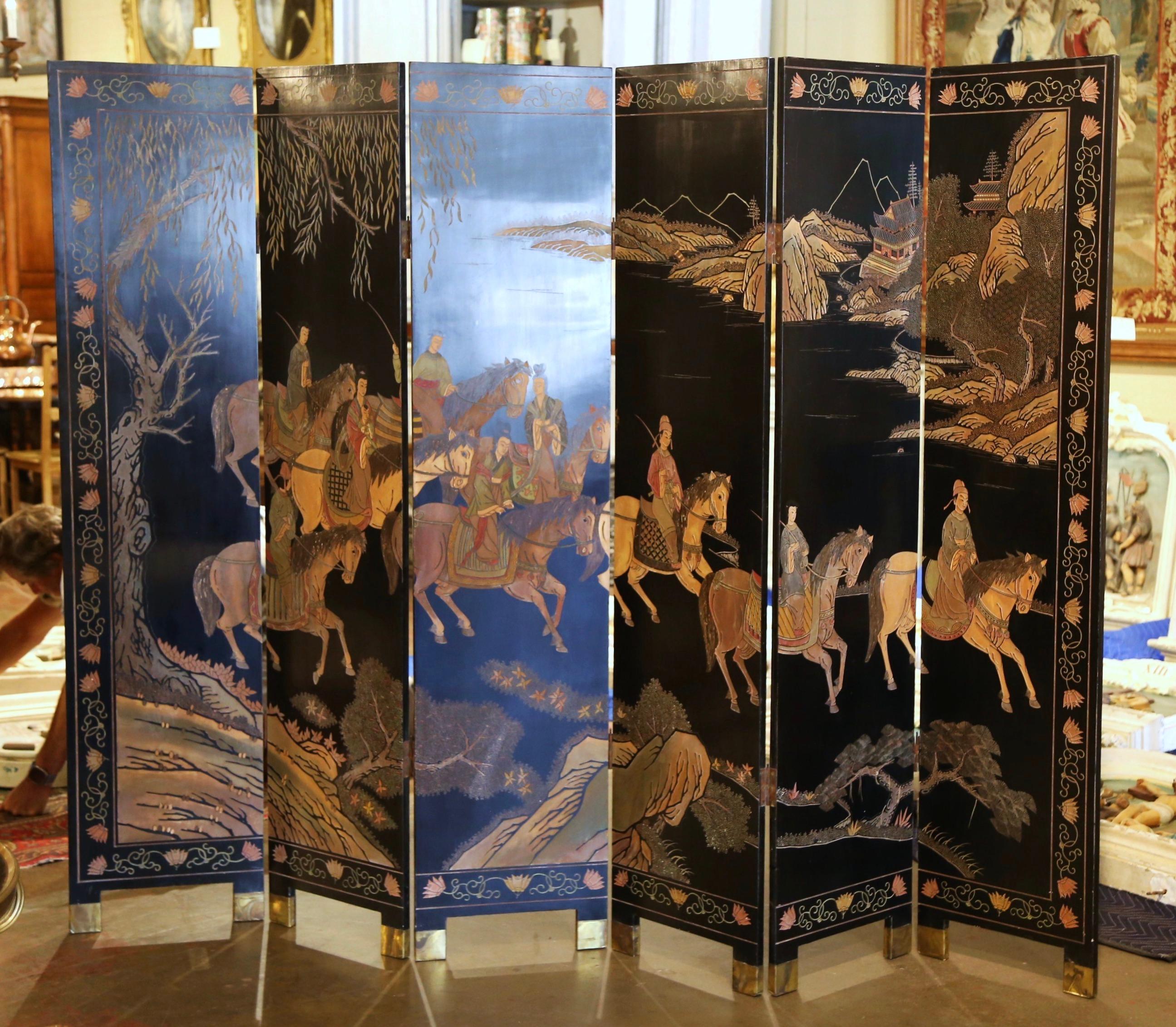 Divide a room or decorate a living room wall with this elegant antique folding screen. Crafted in China circa 1920, the free standing screen stands on bracket feet dressed with brass sabots; it features six lacquered panels decorated with incised