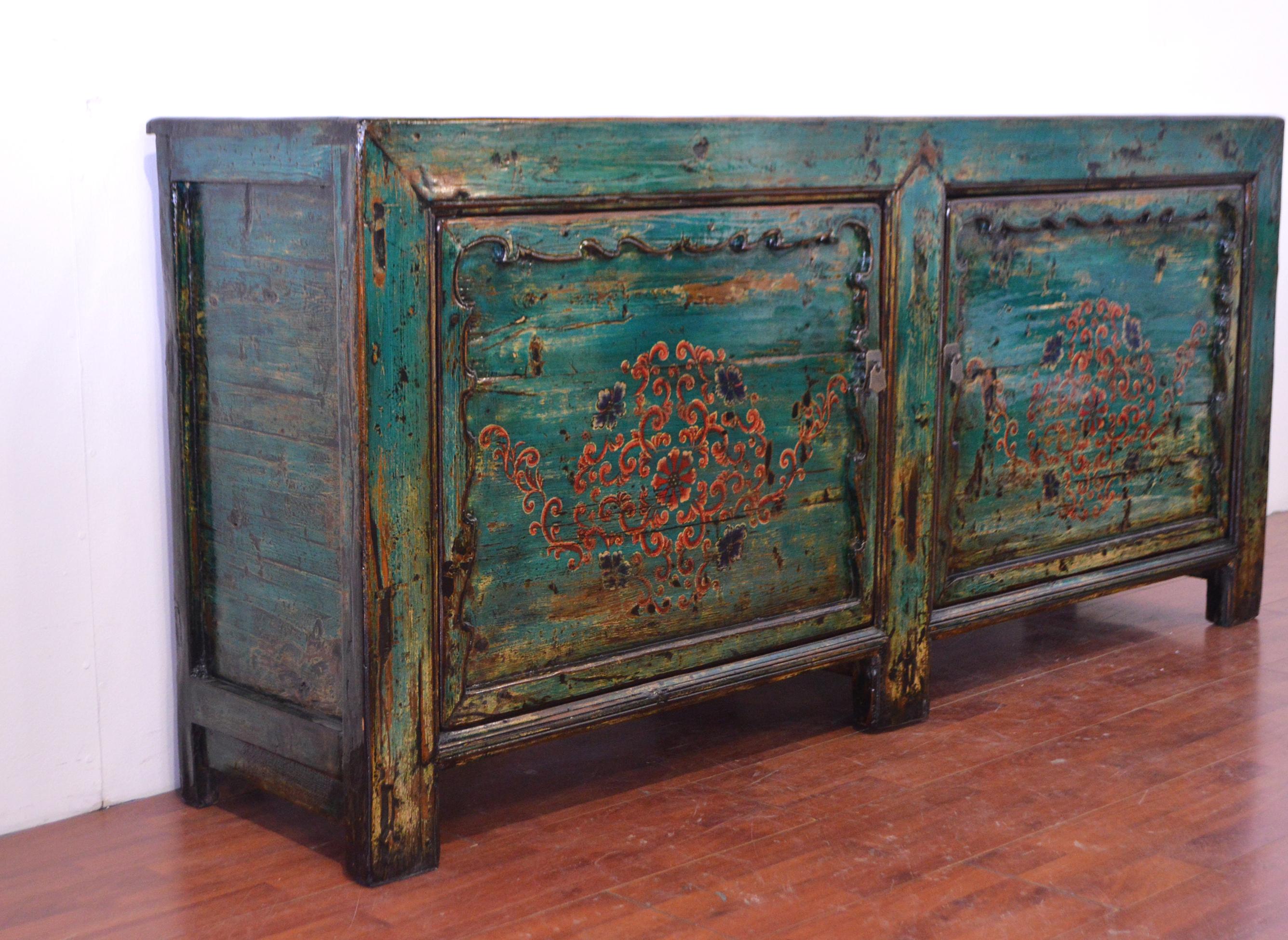 This early 20th century Chinese buffet amazes for its colour: it is composed by two big doors entirely green lacquered like the top where we can see the wood veining. The design on the doors take inspiration from traditional Tibetan decorative art,