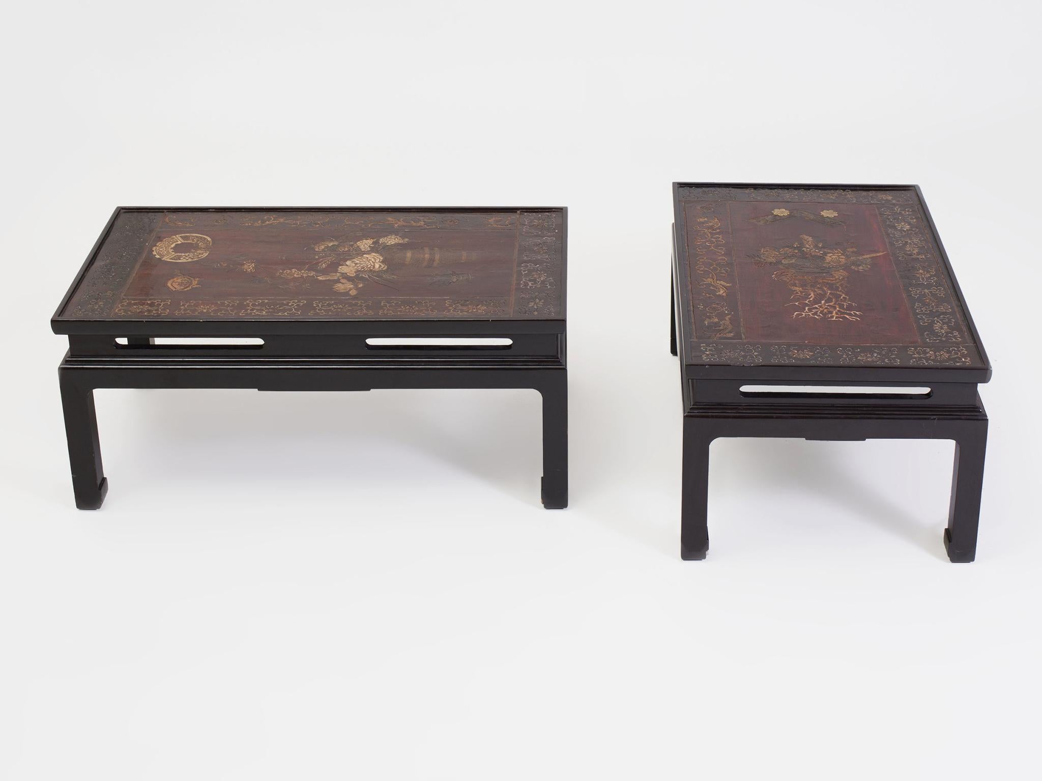 These two Chinese low tables were created in the Early 20th century. They are comprised of wood panels mounted as floating tabletops. The panels are coated with Coromandel lacquer and designed with intricately incised patterns. Floral still-life
