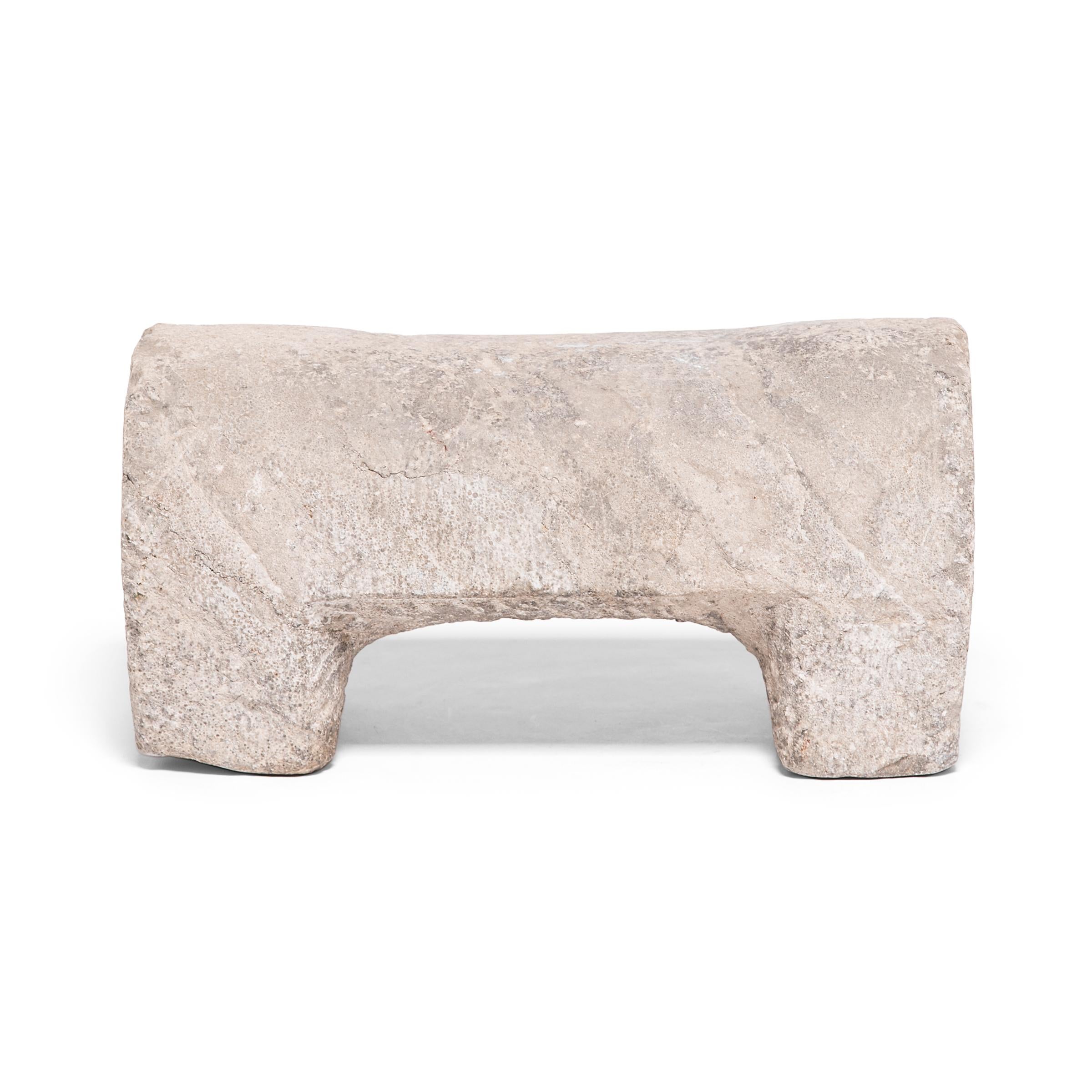 This early 20th century foot rest from China's Shanxi province is simply designed with a rounded body and four square feet. Hand carved of limestone, the footstool is patterned with rhythmic etchings and adorned on the ends with an eight-sided star,