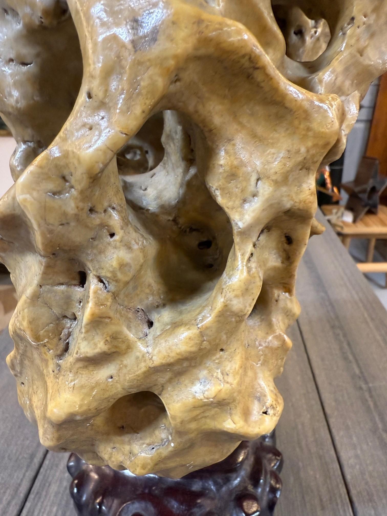 Early 20th century Chinese lingbi scholar's rock on a custom carved wooden stand. Scholar's rocks, also known as 'gongshi' or 'lingbi stones,' are naturally occurring stones that have been appreciated in Chinese culture for centuries for their