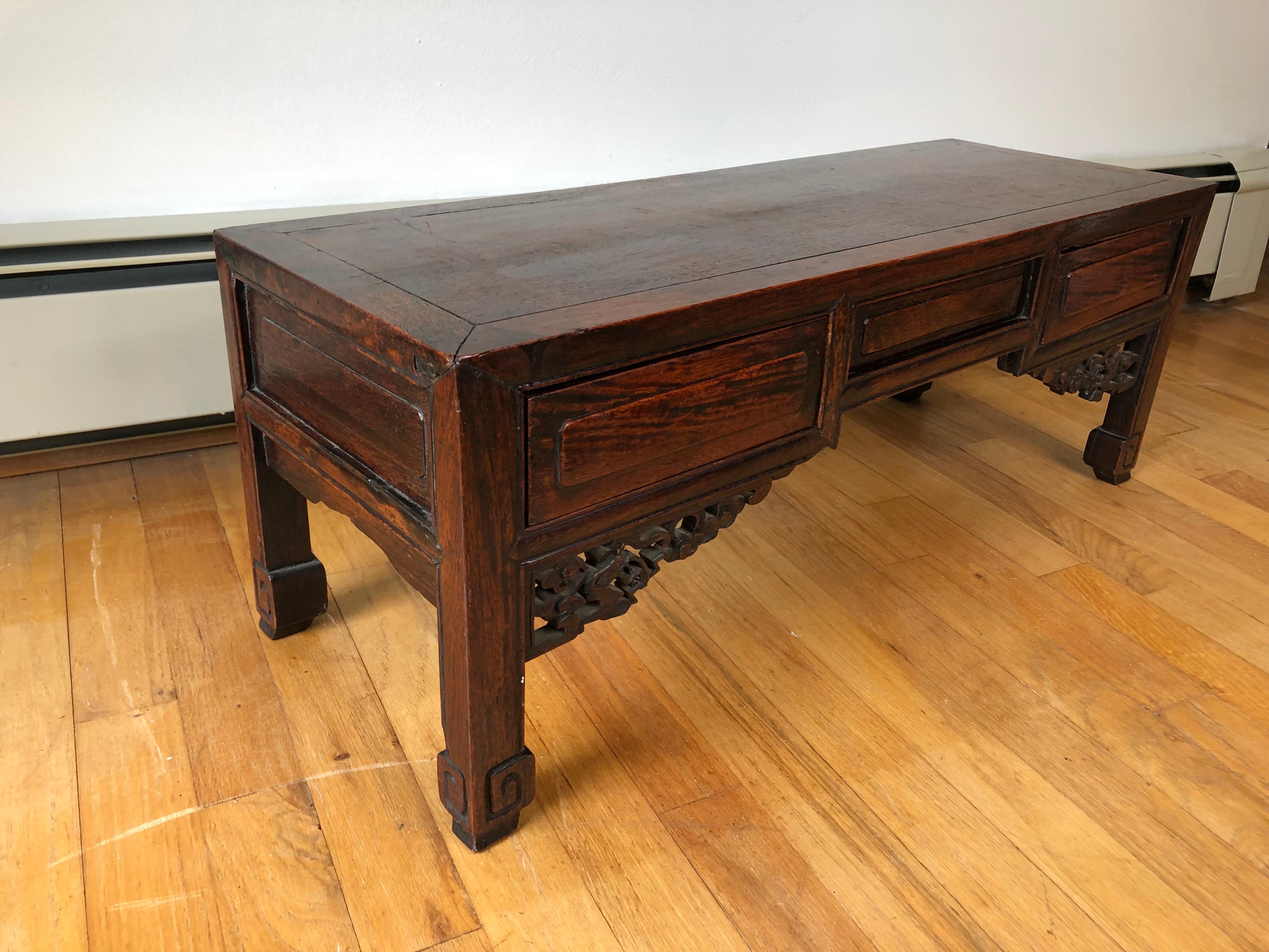 An early 20th century Chinese low table with two drawers and carved brackets.