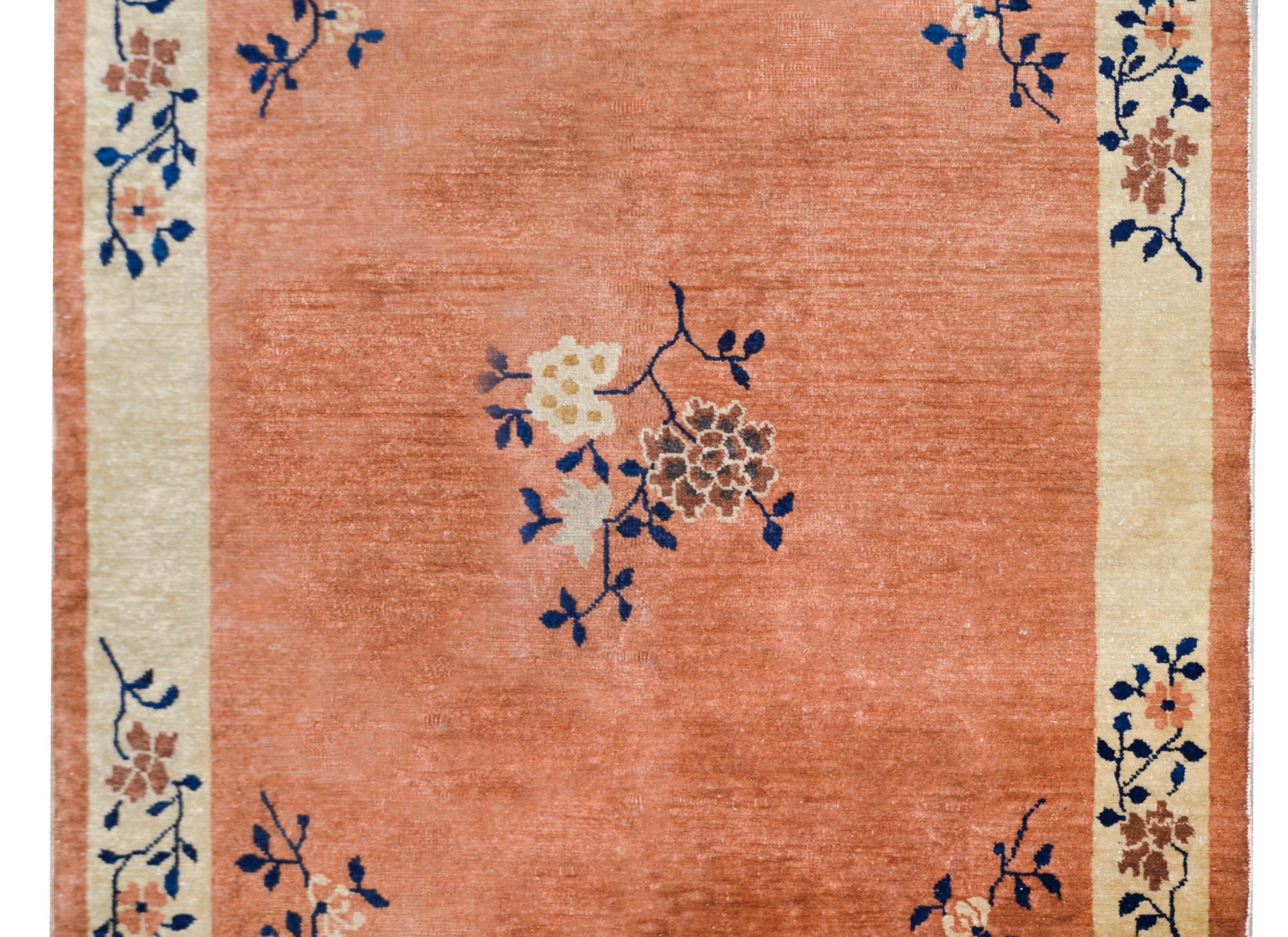 A chic early 20th century Chinese Mandarin rug with a pale orange field with a cream colored striped border with a central peony medallion with chrysanthemums in each corner, and more peonies covering the border.