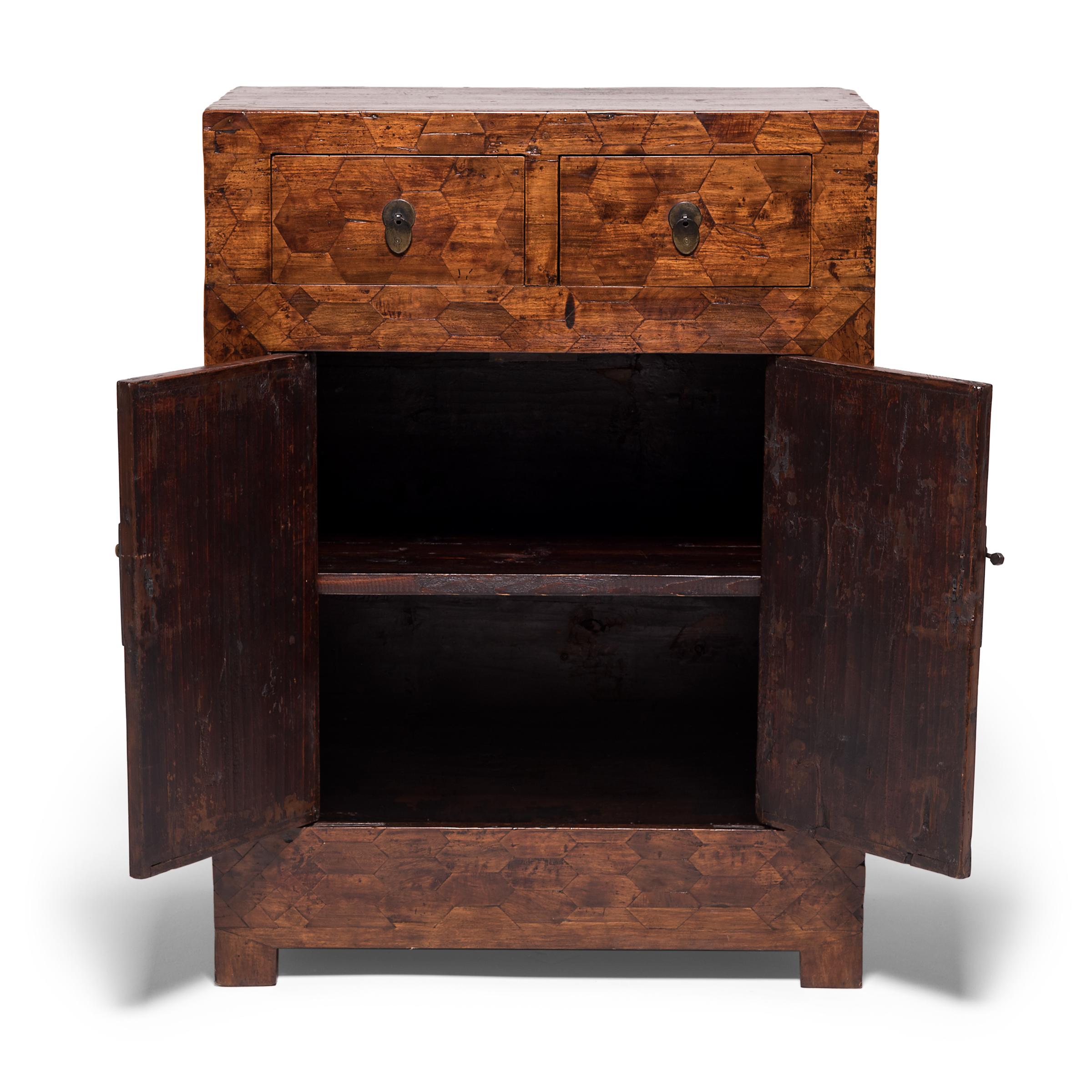 A rare find in Chinese furniture, the entire front of this unusual early 20th century cabinet is covered in parquetry veneer, a complex, decorative carpentry technique of matching precision-cut blocks of inlaid wood. The top and bottom portions of