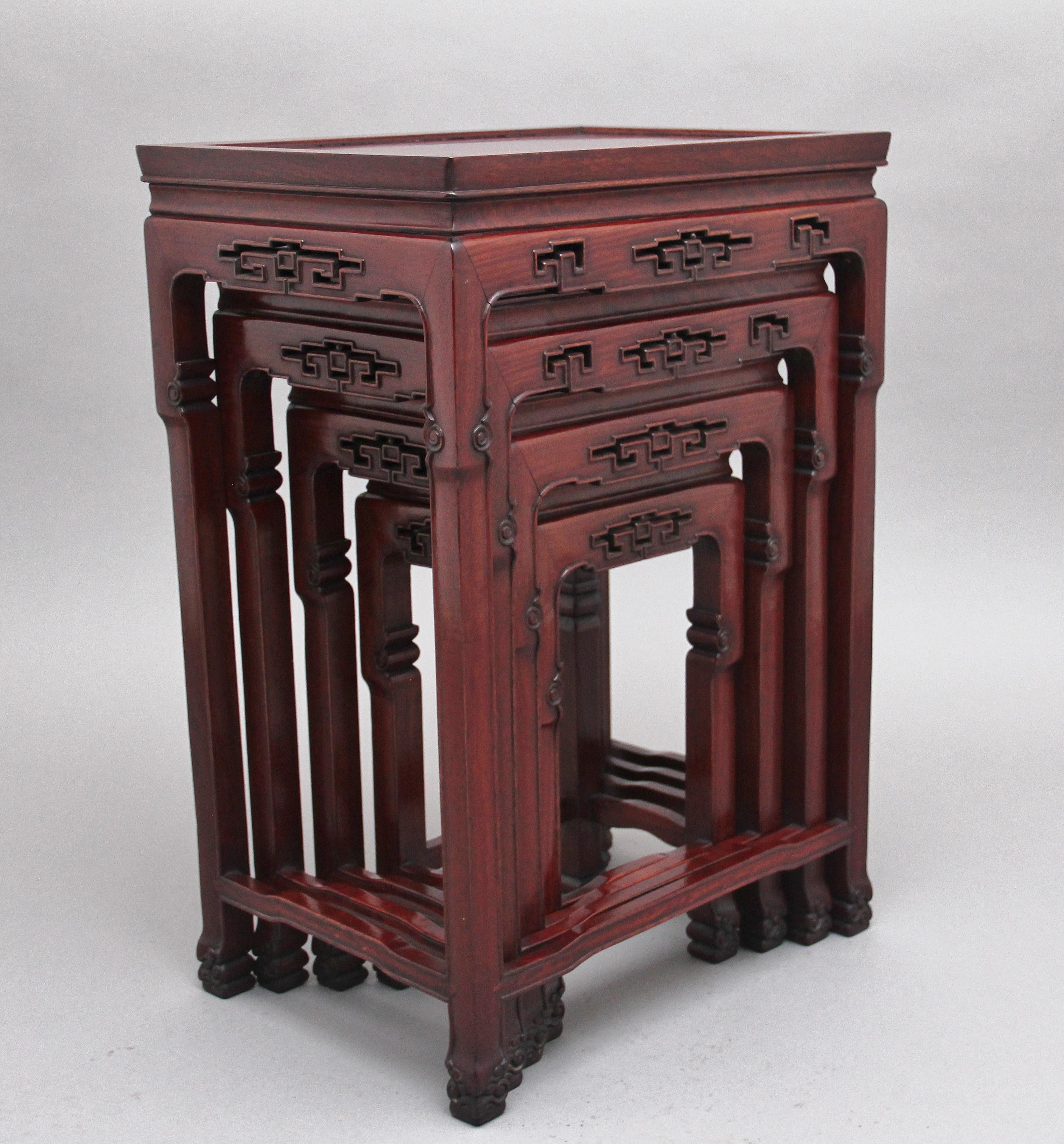 Early 20th century Chinese hardwood nest of four tables, having moulded tops supported on pierced and carved square legs united by shaped stretchers, terminating on decorative carved scroll feet, Circa 1910.
  