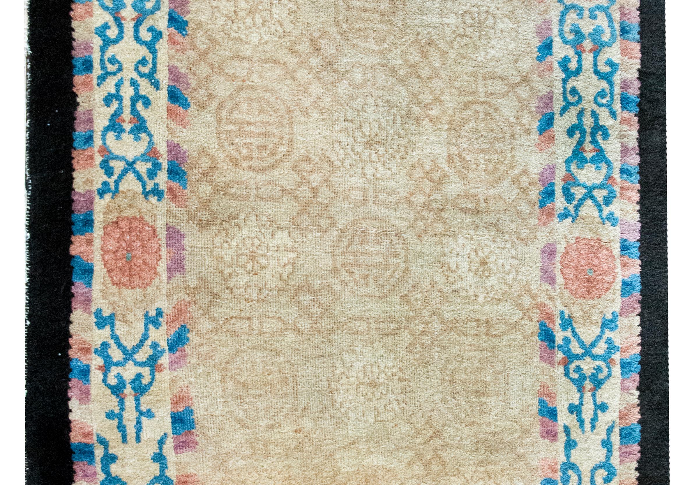 A wonderful early 20th century Chinese Peking oval rug with a central field woven with a subtle tone on tone Shou character and peony pattern, and surrounded by a charming border with large pink peonies and indigo scrolling vines.
