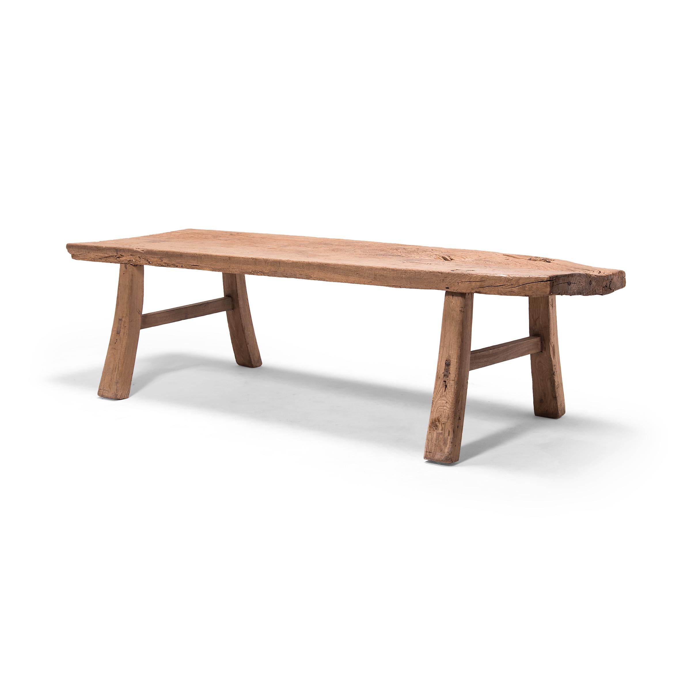 This provincial bench from China's Shanxi province features a plank-top surface supported by gently splayed legs with simple stretcher bars. Constructed with mortise-and-tenon joinery techniques, without the use of nails or screws, the broad bench