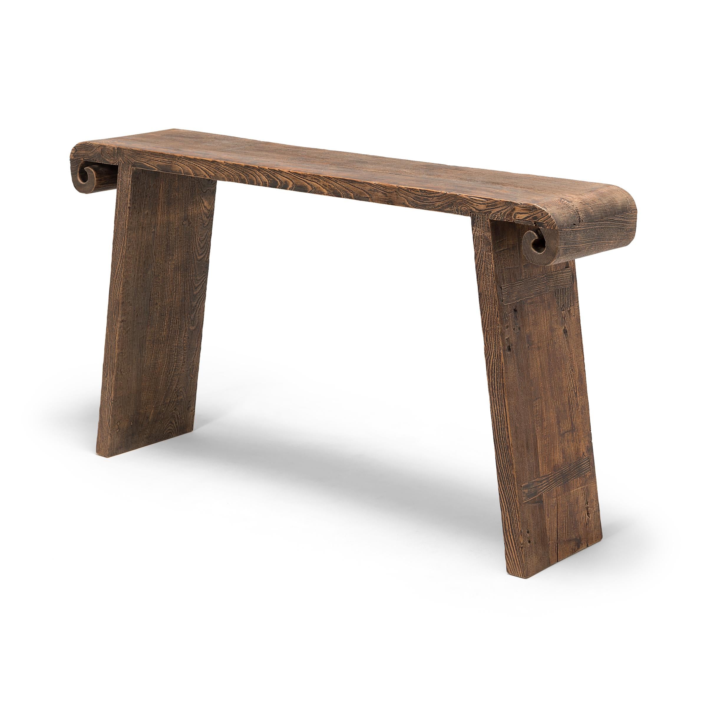 With no stretchers or spandrels, this elegant early 20th century altar table resembles one continuous ribbon. Carefully assembled with mortise-and-tenon joinery, the table's plank top surface ends in two scrolled edges, evoking the image of an