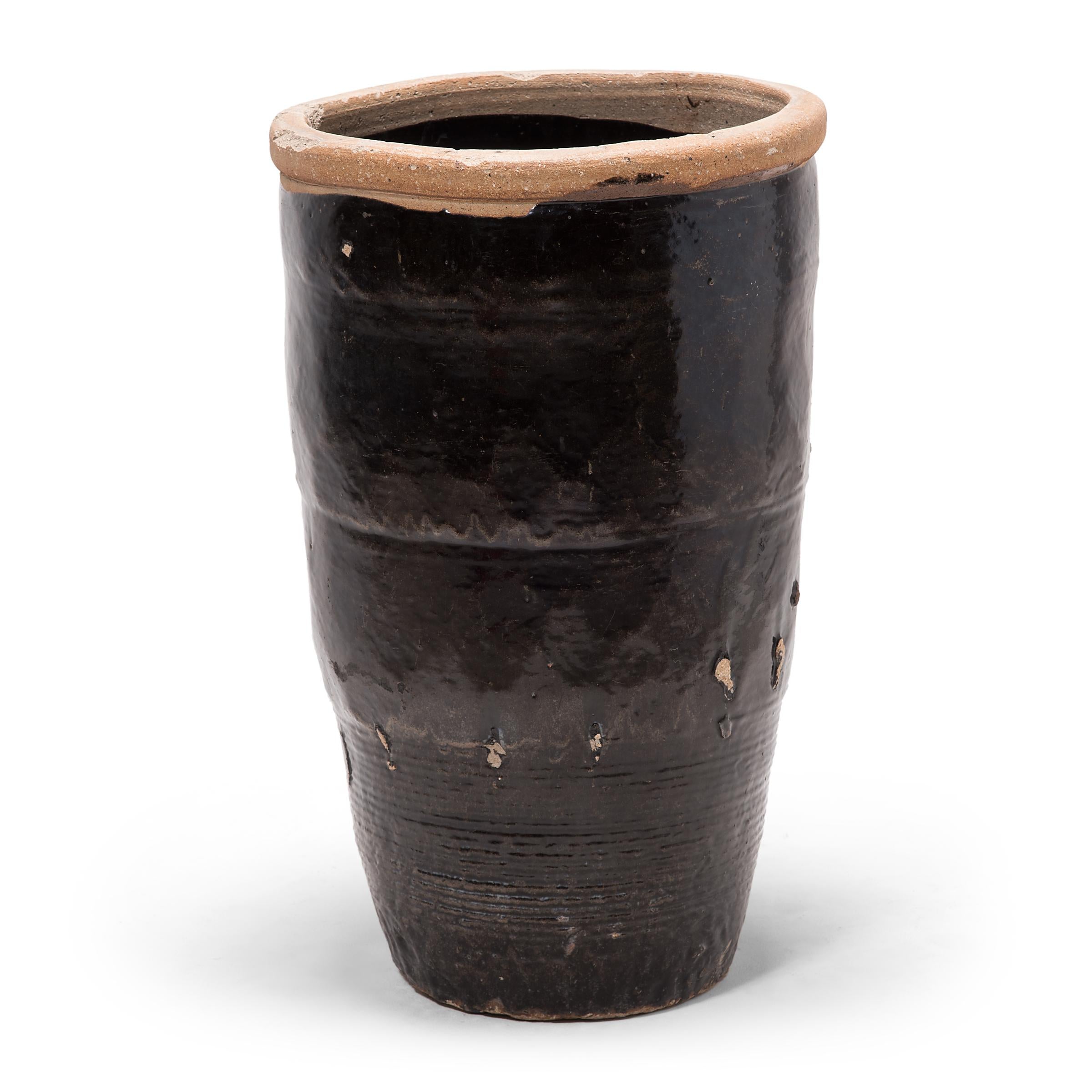 Originally used for pickling foods, this monumental early 20th century vessel from China's Shanxi province is coated inside and out with a dark glaze. Subtle ridges at the base suggest that the jar was fashioned by coiling flattened ropes of clay