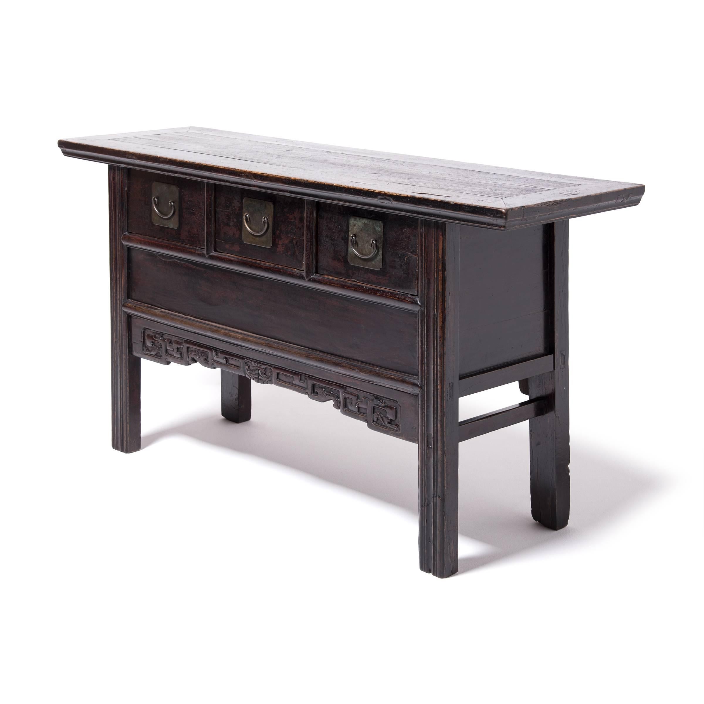The sleek design of this 19th century three drawer table is generally attributed to the minimal style of the Ming period (1368-1644). It was handcrafted in China’s Henan province out of local elmwood. The quality of the workmanship is evident by its
