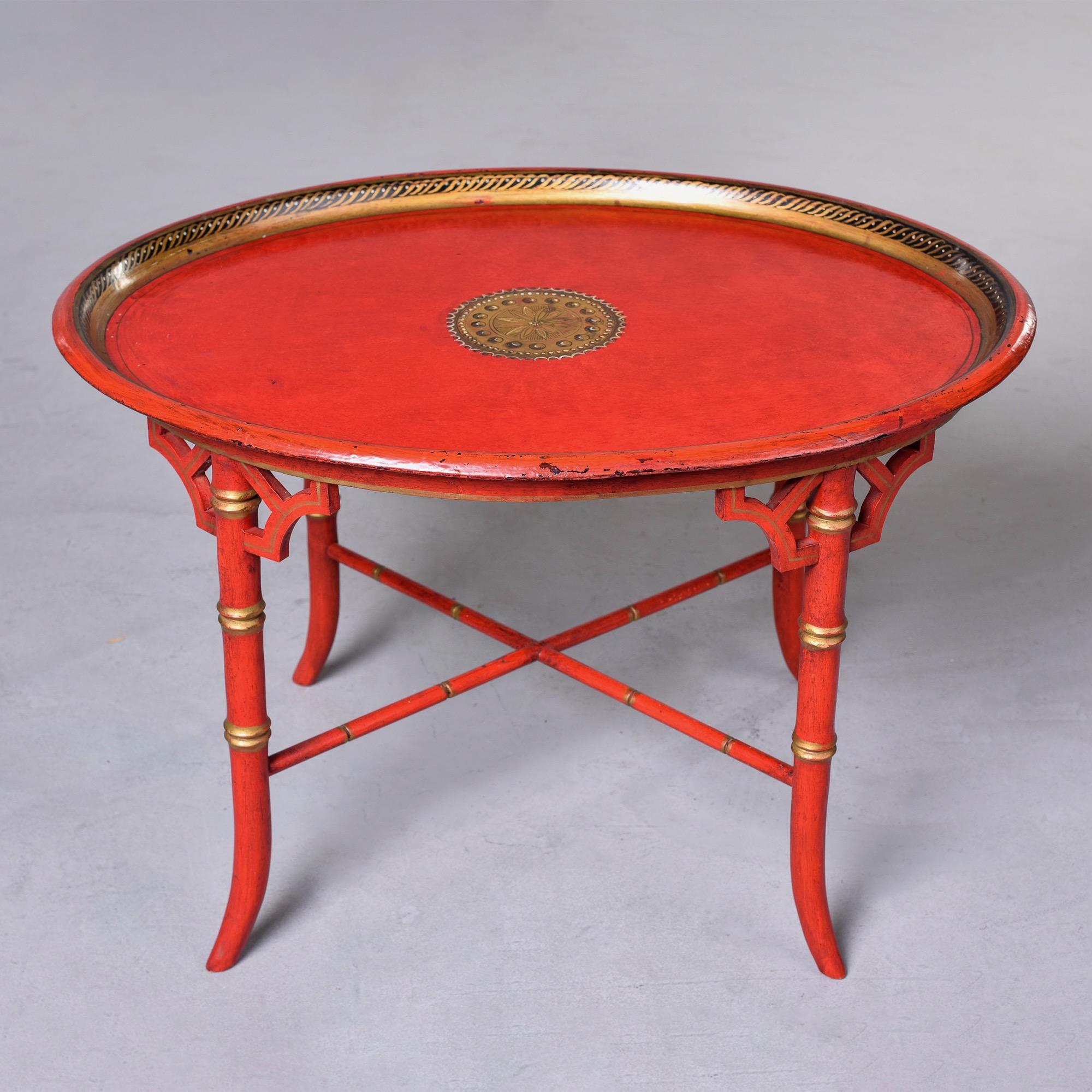 Found in England, this circa 1930s red oval Chinoiserie style side table features a faux bamboo base with X-form stretcher and gilded details. Oval table top has a decorative painted gilt border on inside edge and decorative painted large center