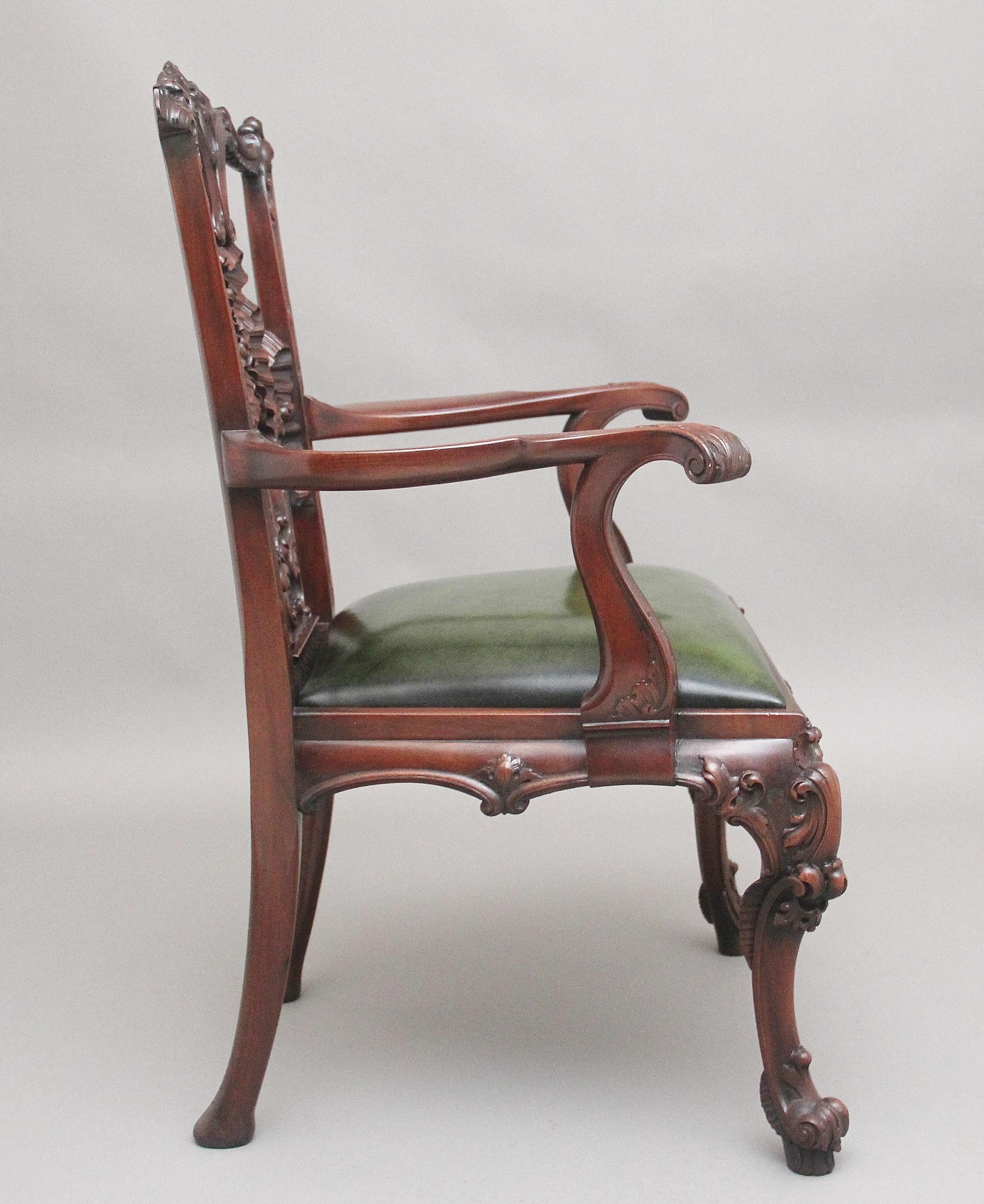 A highly decorative early 20th Century carved mahogany armchair in the Chippendale style, having a wonderfully carved and pierced back splat, the slender curved supports with scroll decoration on the front of the arms, having a re-upholstered