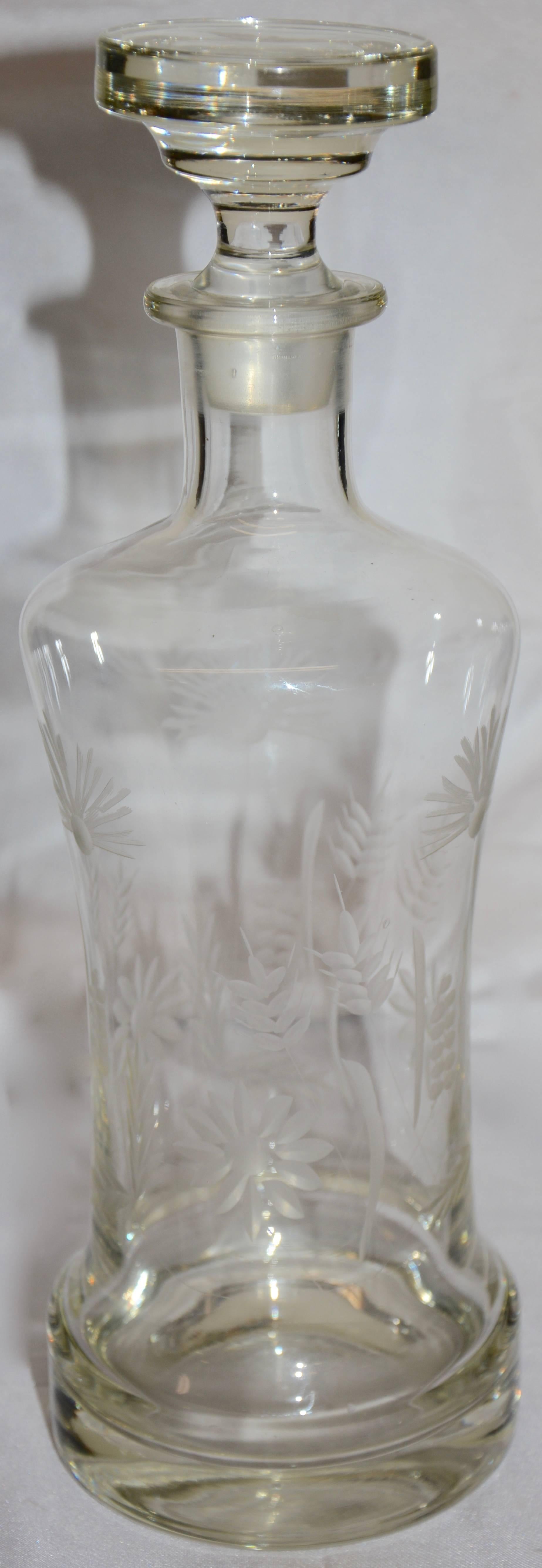 Hand etched floral and foliate details decorate this heavy crystal decanter. It is topped with a flat top stopper. No markings present.