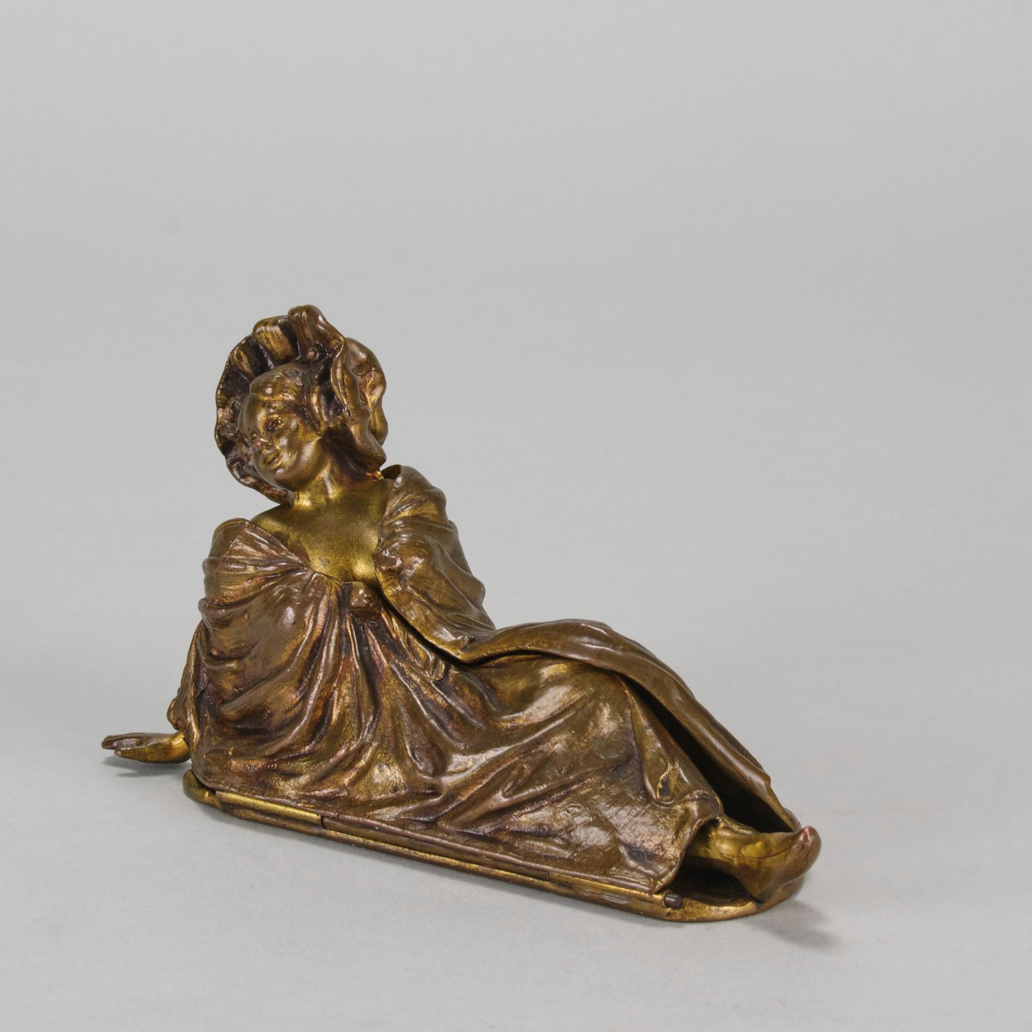 Une jolie figurine en bronze doré du début du 20e siècle représentant une jeune beauté en position allongée, recouverte d'une grande couverture qui s'ouvre pour révéler une tenue affriolante. Les couleurs et les détails sont excellents, signée JB et
