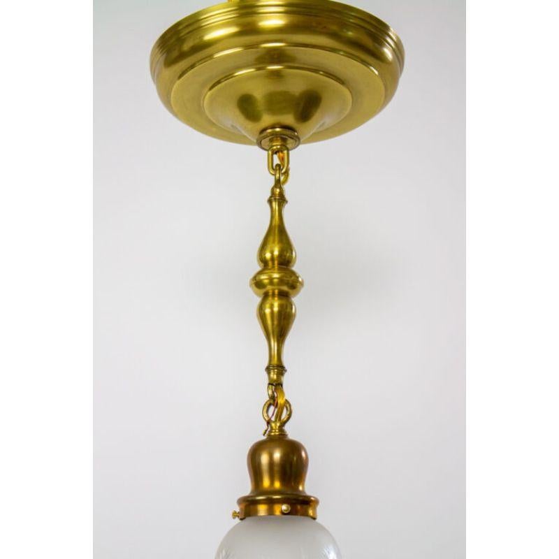 Colonial pendant with cut frosted glass hanging from a brass fixture.

Material: Brass, glass
Style: Traditional, colonial
Place of origin: United States
Period made: Early 20th century
Dimensions: 8 × 8 × 20 in
Condition details: Excellent