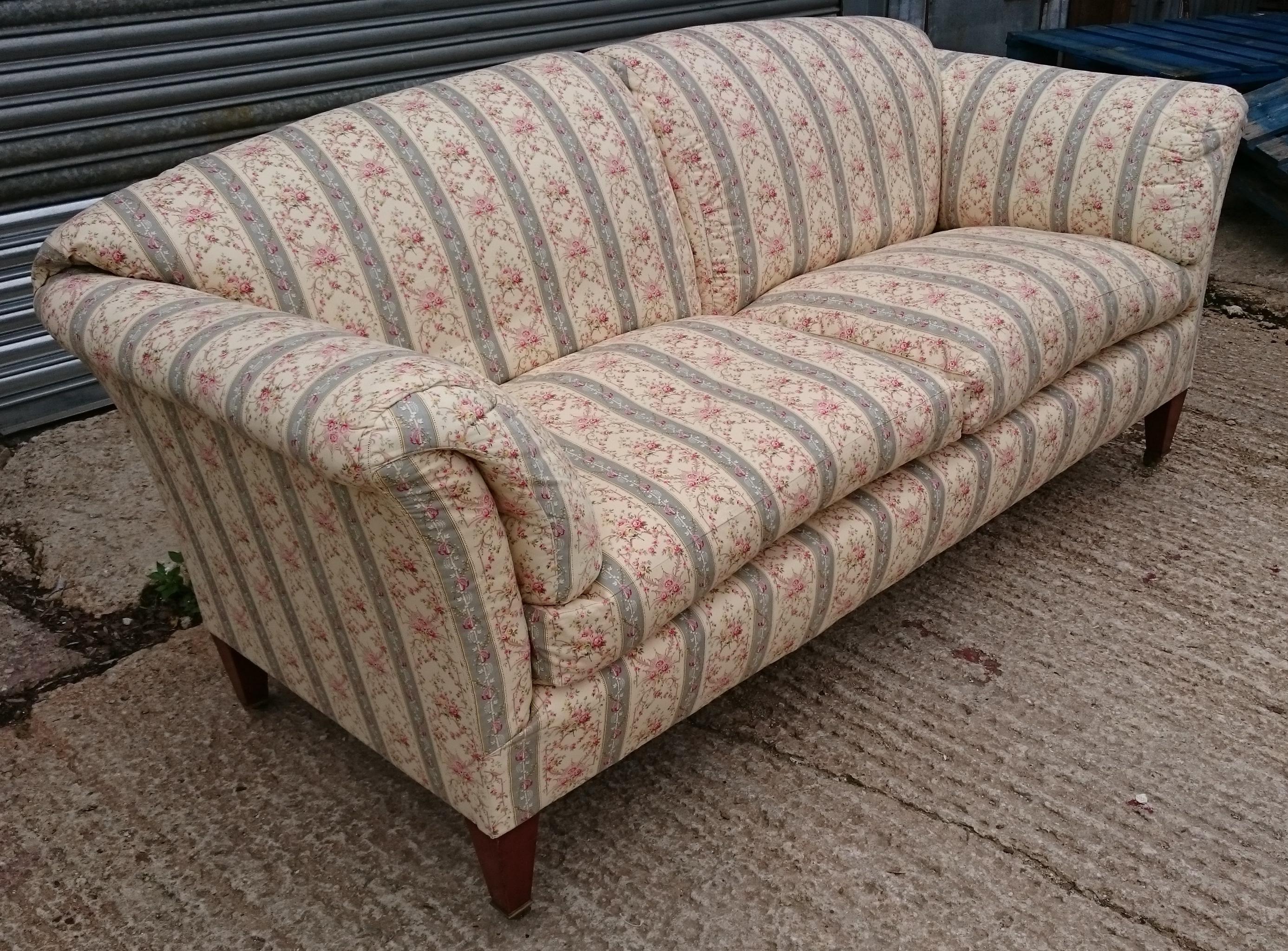 Large and comfortable antique sofa made by Howard and Sons of London. This sofa has been covered in a copy of the original cotton fabric which Howard and Sons used to upholster a piece under a loose cover. There are feather cushions built into the