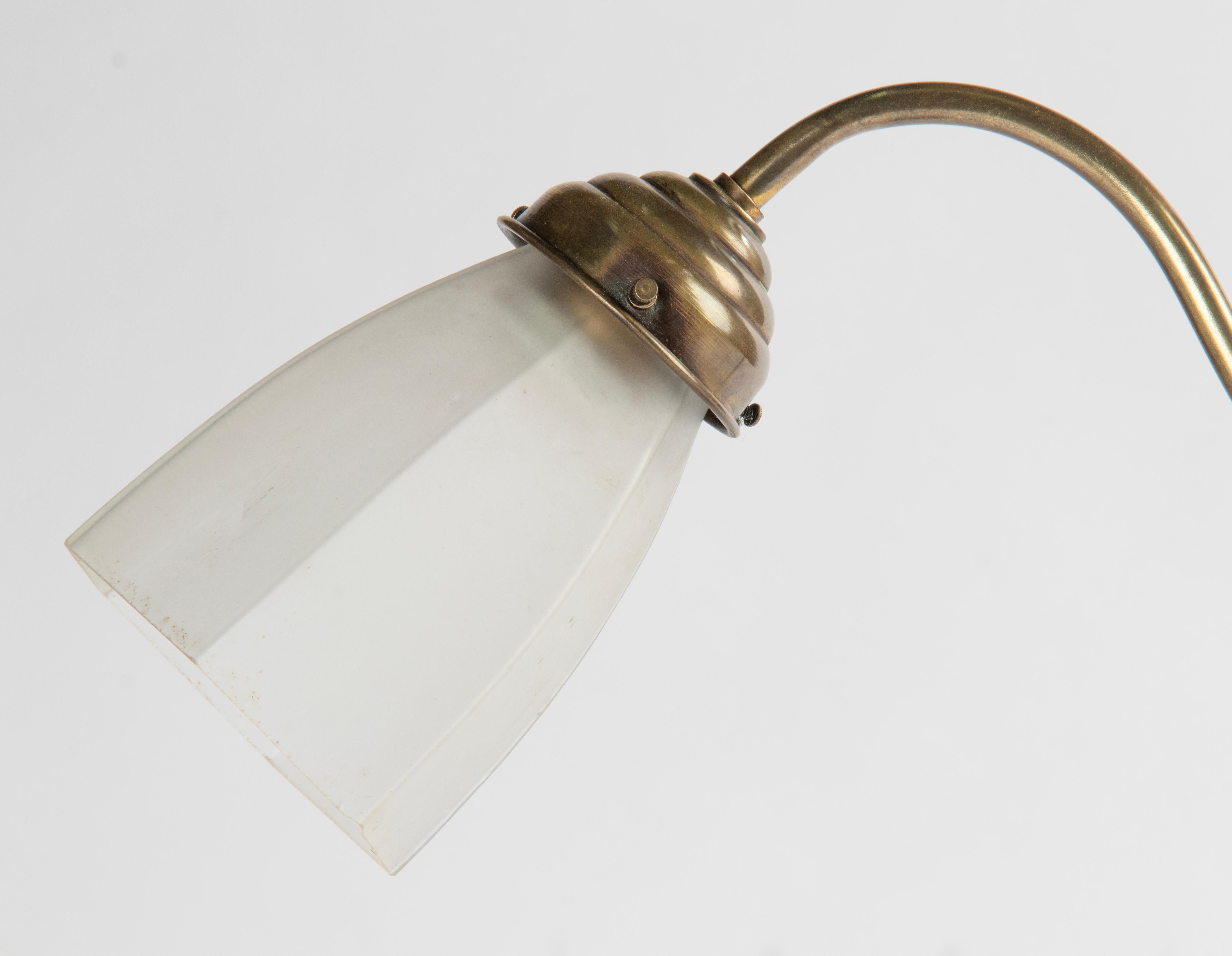 Une élégante lampe de table ou de bureau ancienne, avec un abat-jour en verre ancien. La base et la tige sont en cuivre. Sur le dessus, un anneau pour remplacer la lampe, décoré d'un gland et d'une feuille de chêne. La lampe est réglable en hauteur.