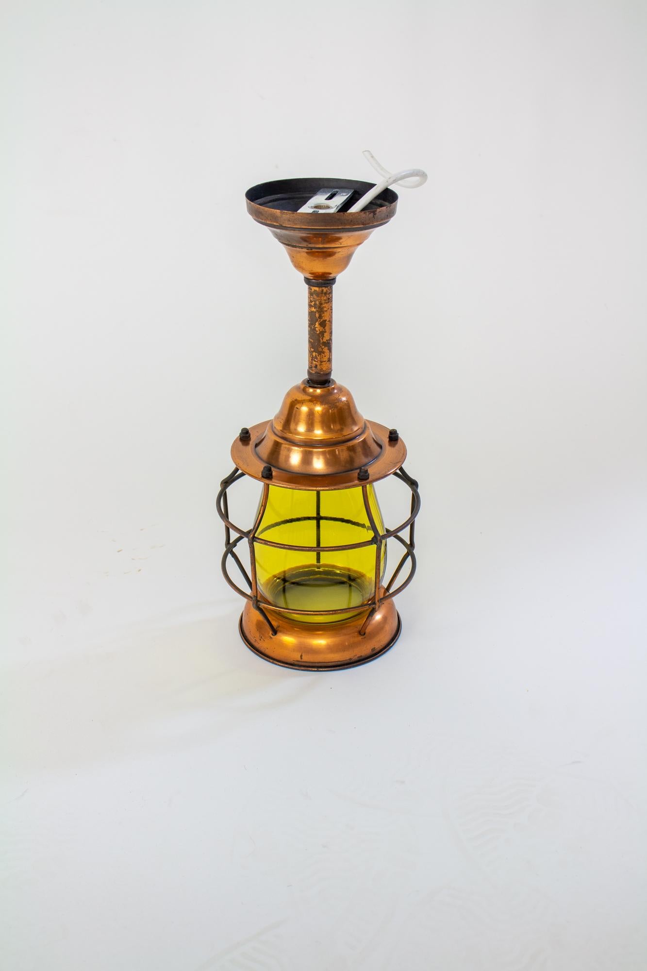 Early 20th Century copper nautical lantern with amber glass. Caged fixture with an open copper ring at the bottom, which unscrews to provide access to the light bulb. Cage is a darkened metal, bottom and crown are a copper finish, as is the tube and