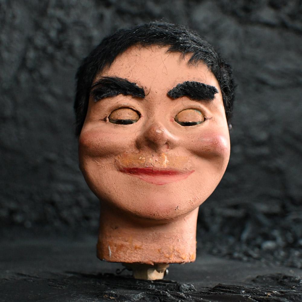 Early 20th century Creepy Glass Eyed English puppet head.  
Creepy indeed, is this early to mid-20th century articulated English ventriloquist dummy’s head. Made from a composite material and secured to a pine neck base. When the neck lever is
