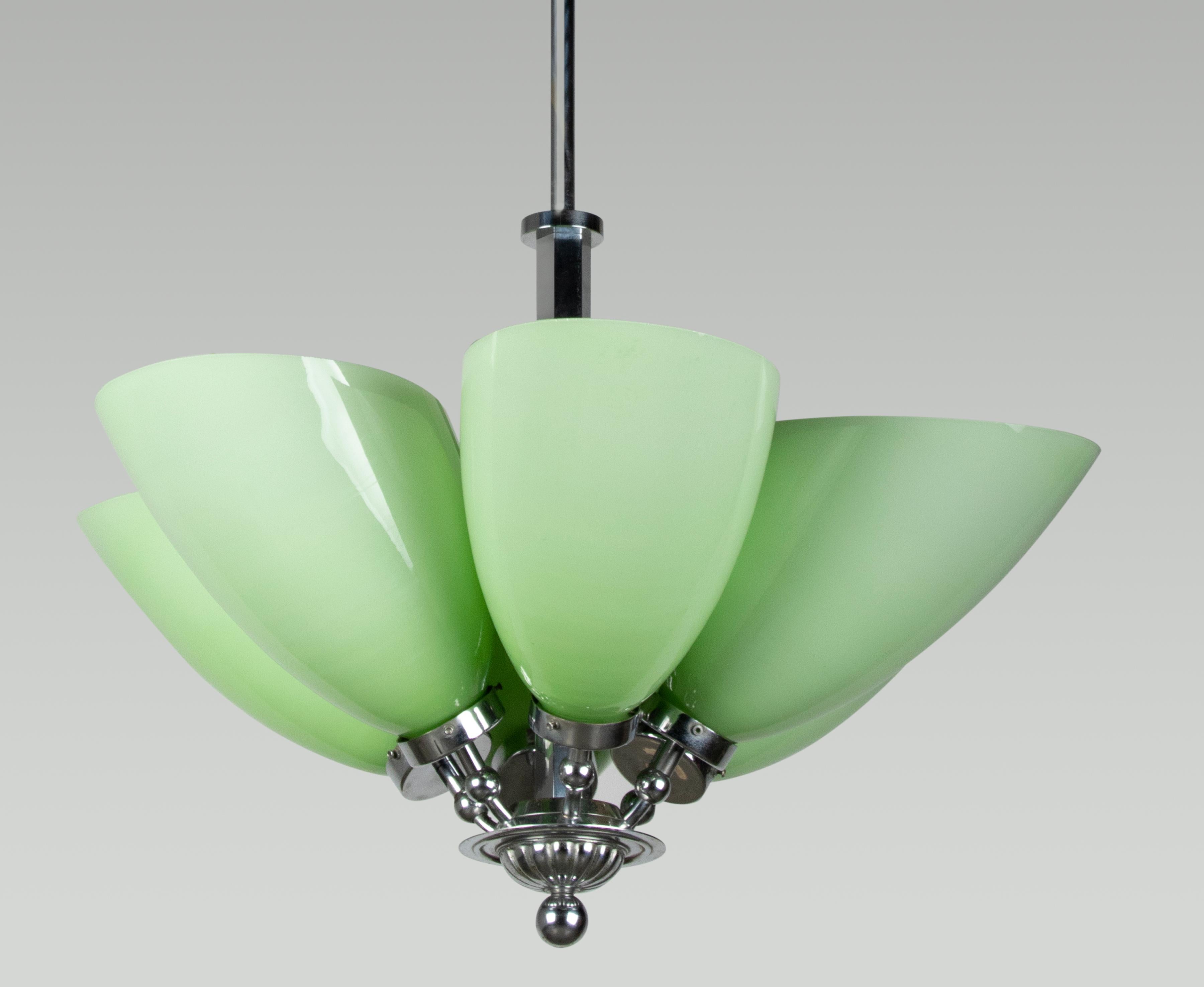 Schöner Art-Deco-Kronleuchter mit großen grünen Glasschirmen. Die Leuchte ist aus verchromtem Metall gefertigt. Die Glasschirme sind aus Opalglas gefertigt, das einen subtilen Farbverlauf von hellem zu dunklerem Grün aufweist. Die Lampe spendet ein