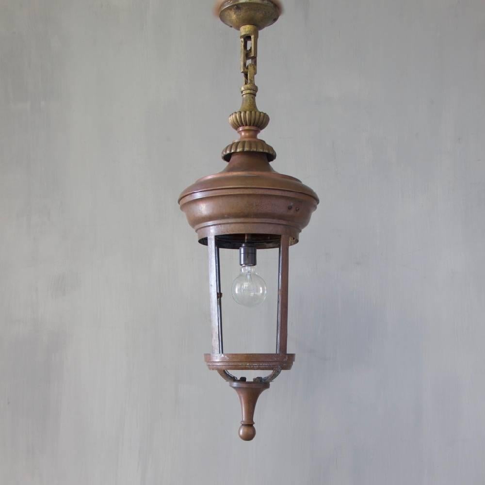A cylindrical copper hanging lantern with original brass chain and ceiling canopy, England, circa 1930.