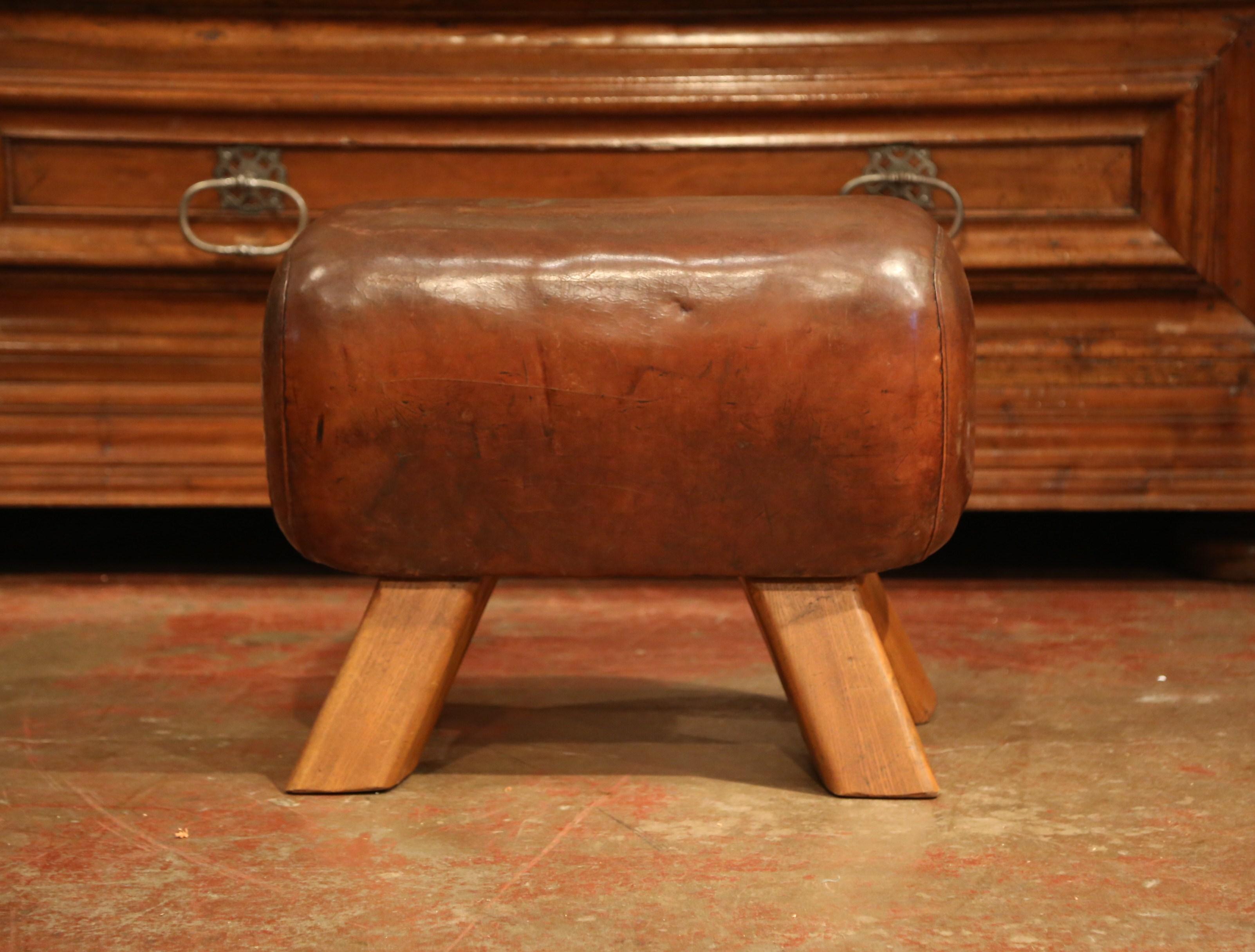 This antique, gymnasium pommel horse bench was crafted in the Czech Republic, circa 1920. The rustic stool sits on four angled wooden legs; the seat is upholstered with the original patinated leather. This sturdy piece is in excellent condition and