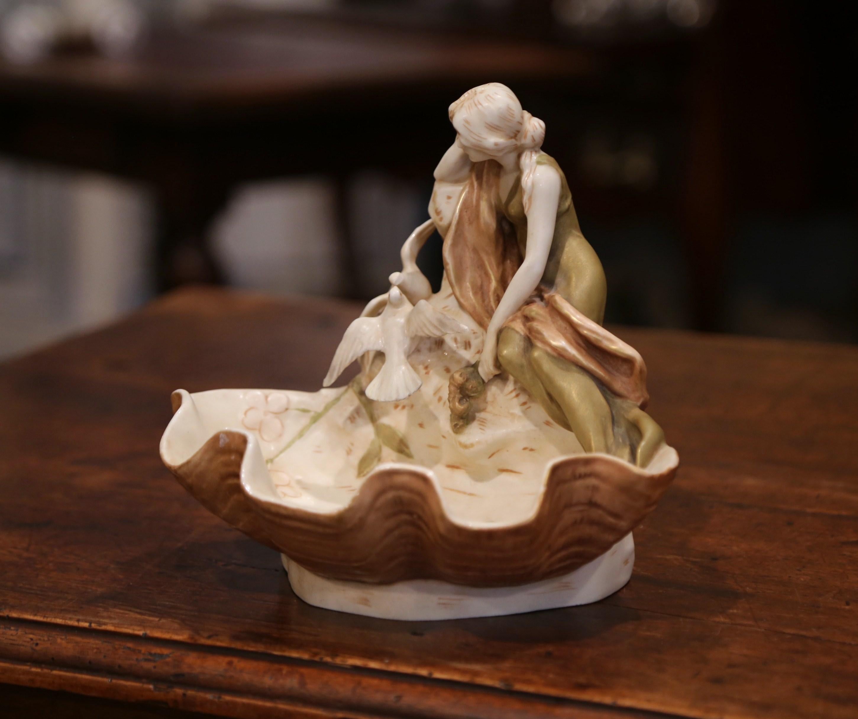 Place this decorative porcelain dish on your entry commode to collect loose change! Crafted in the Czech Republic circa 1930, the art deco sculpture features a woman statue sited on the edge of a basin with two doves on her side. The carved
