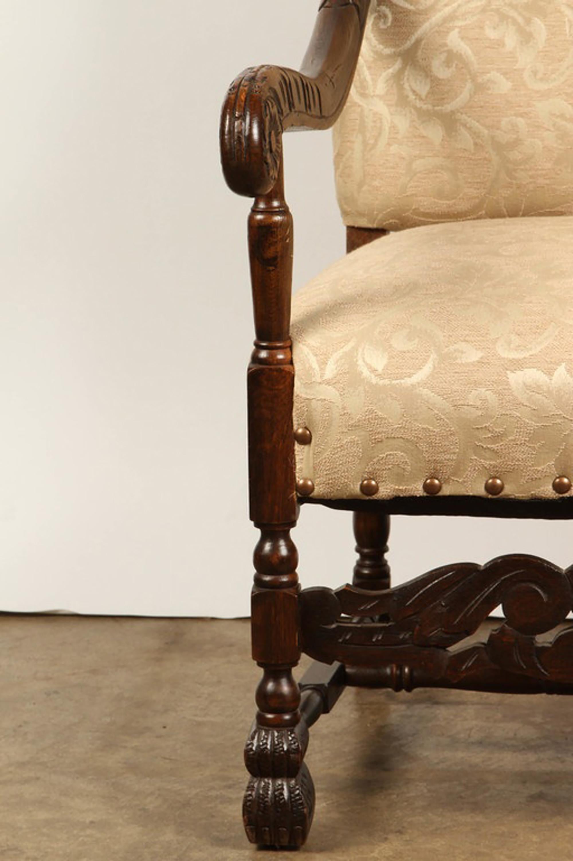 An early 20th Century carved oak Danish baroque revival chair. The upholstery for this Danish revival chair is new. It has a leaf and vine pattern in light shades of cream and white, and rows of golden studs at the bottom edges of the seat. The