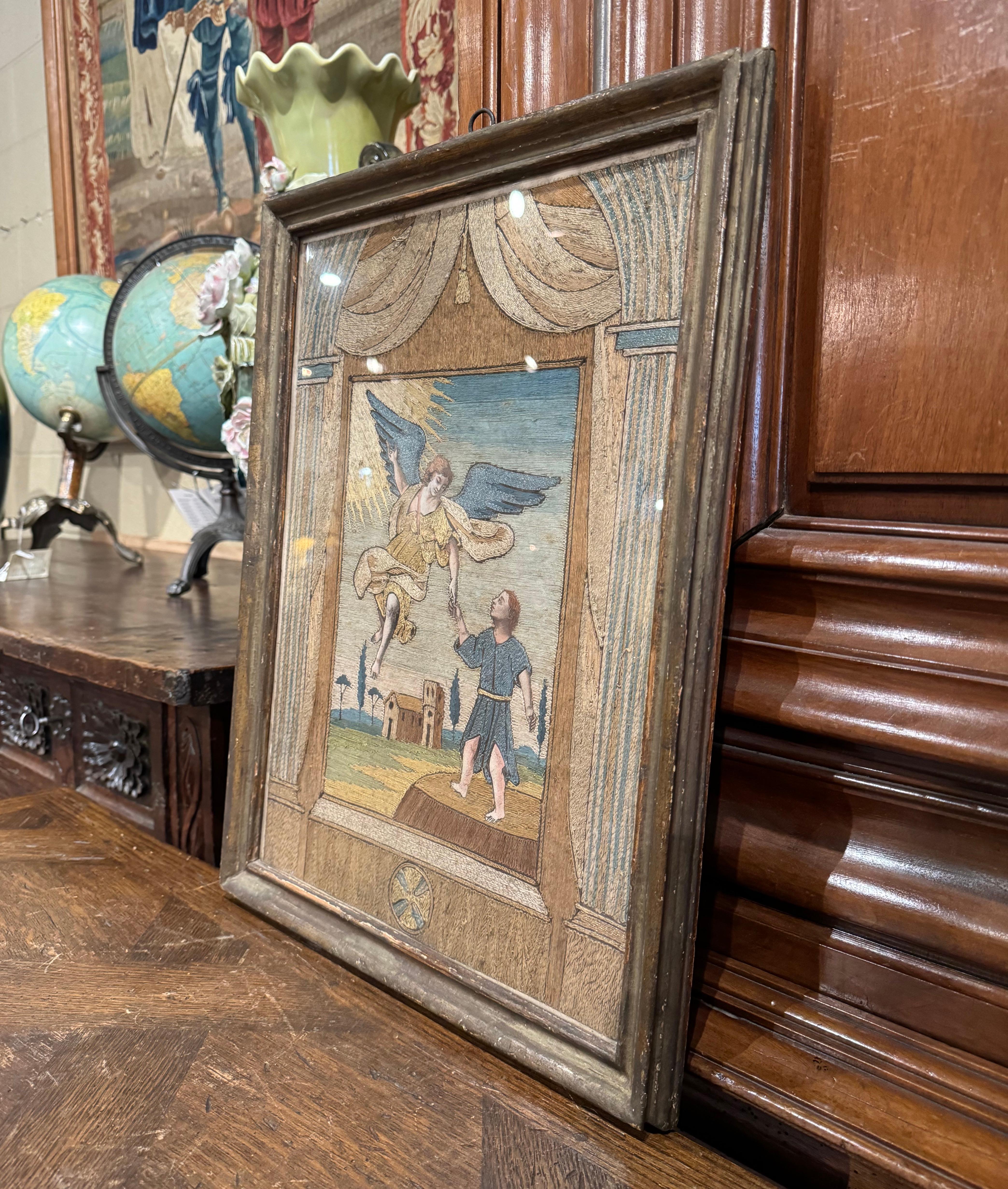 Decorate a study or hallway with this elegant and colorful wall decor. Hand crafted in Denmark circa 1937 set in a frame protected with glass, the panel depicts an angel reaching down from the heavens to guide a young man. Depicted in the background