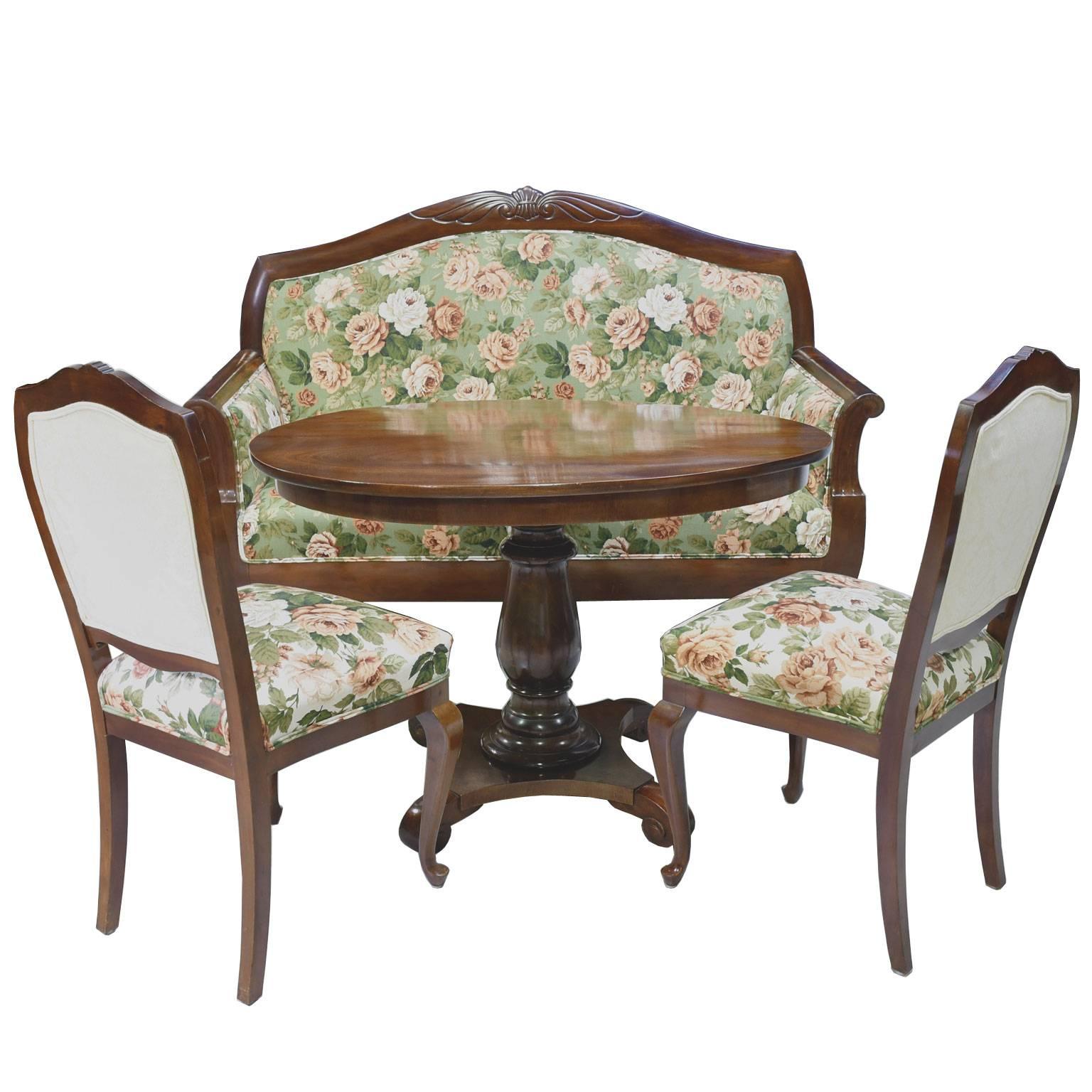 A very beautiful pre-World War I parlor suite in fine West Indies mahogany, comprising of a sofa, two chairs and oval table. Sofa and chairs have an arched back with carving of a shell flanked by wings on the crest rail, with upholstered seat and