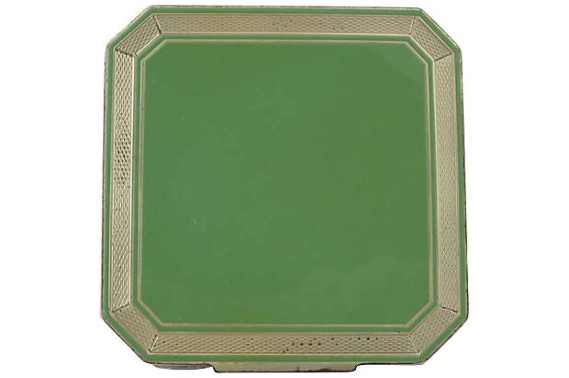 Art Deco sterling silver compact featuring a square green enamel center with an engine-turned frame and back. The compact opens to a mirror (crack on corner) and an interior powder compartment. Retains the original screen and a pink puff (which is