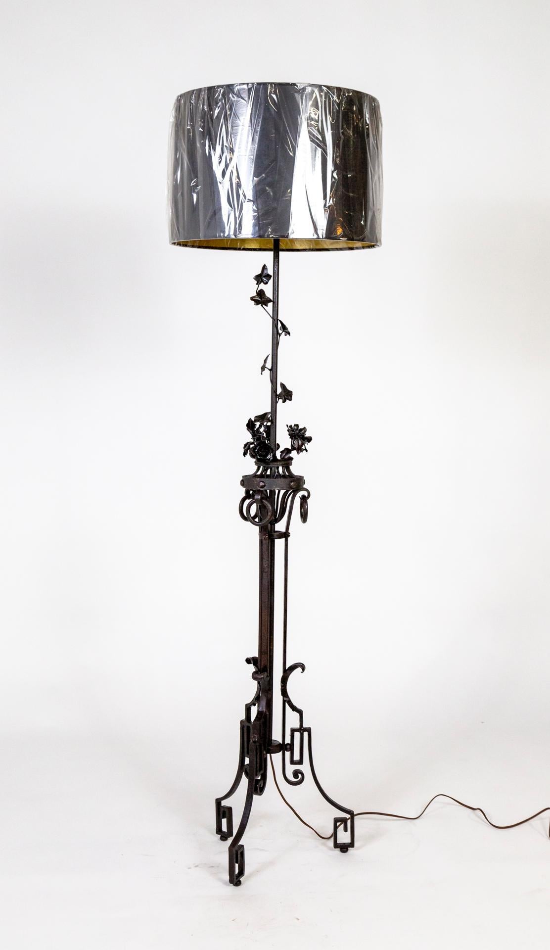 Eine französische Stehlampe aus handgeschmiedetem Eisen, Art Deco, um 1910, mit einem dreibeinigen Sockel mit griechischem Schlüssel und Jugendstilverzierungen. Blumen und Ranken ranken aus einem mittleren Korb, der mit schweren Eisenringen verziert