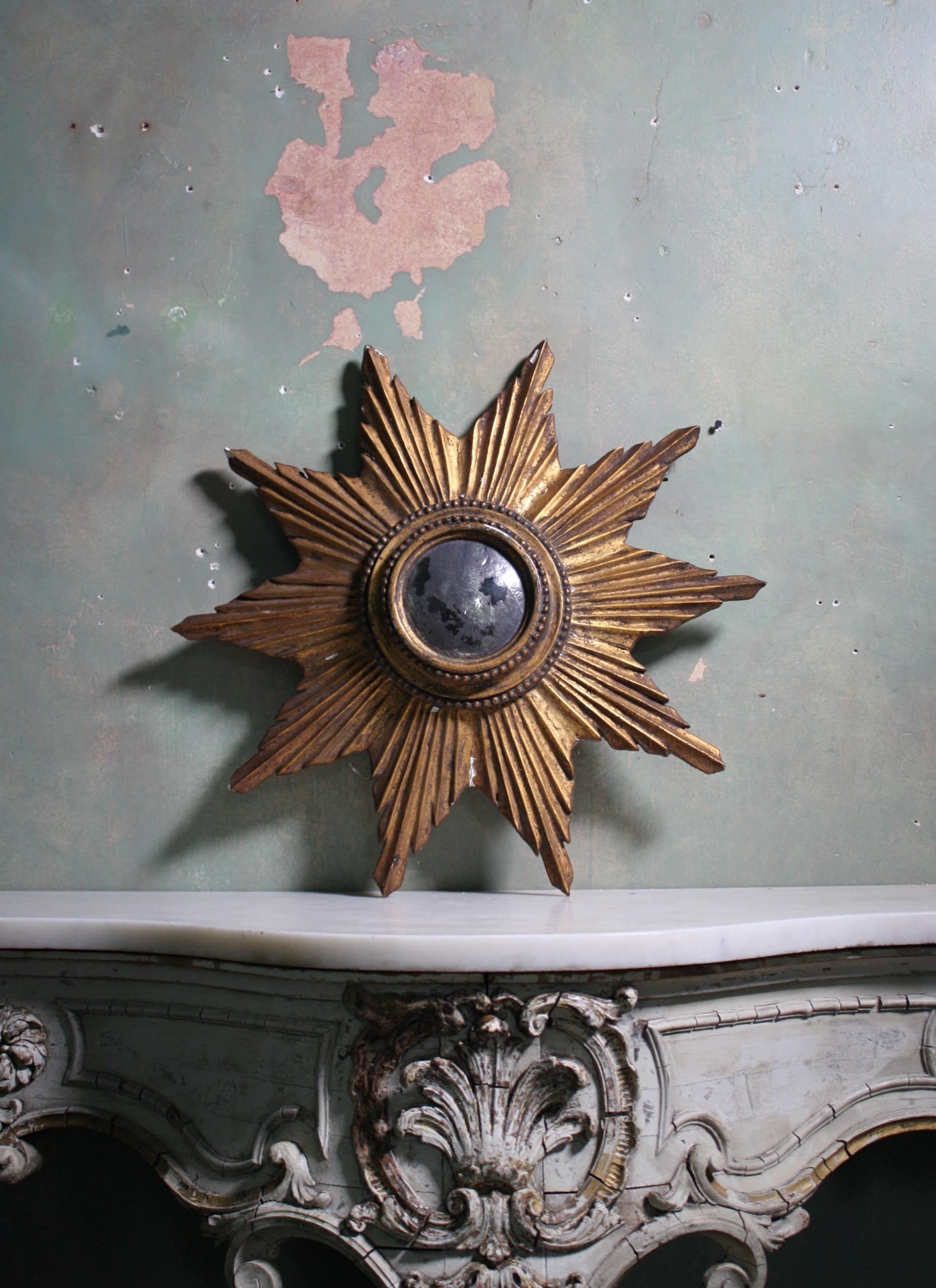 A beautiful and untouched early 20th century sun burst mirror, with a heavily oxidized circular convex mirror.

The gilt gesso work has age related wear and discoloration, some small sections of loss.

European in origin, likely to be