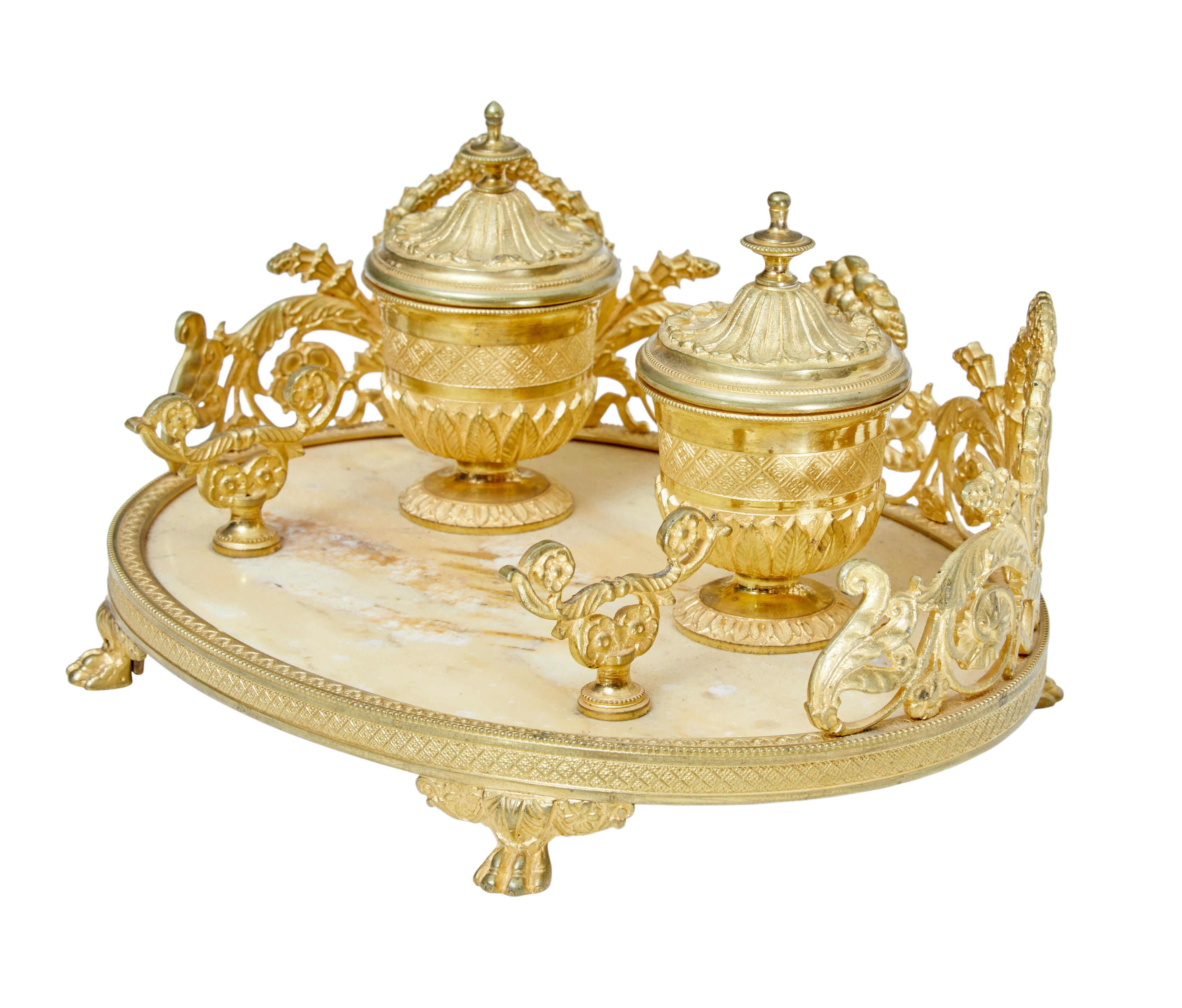 Fine quality double inkwell, circa 1900.

Oval shape with a marble base, pierced gilt gallery which forms the backdrop for the 2 inkwells and 2 pen rests.

1 replaced ceramic pot.