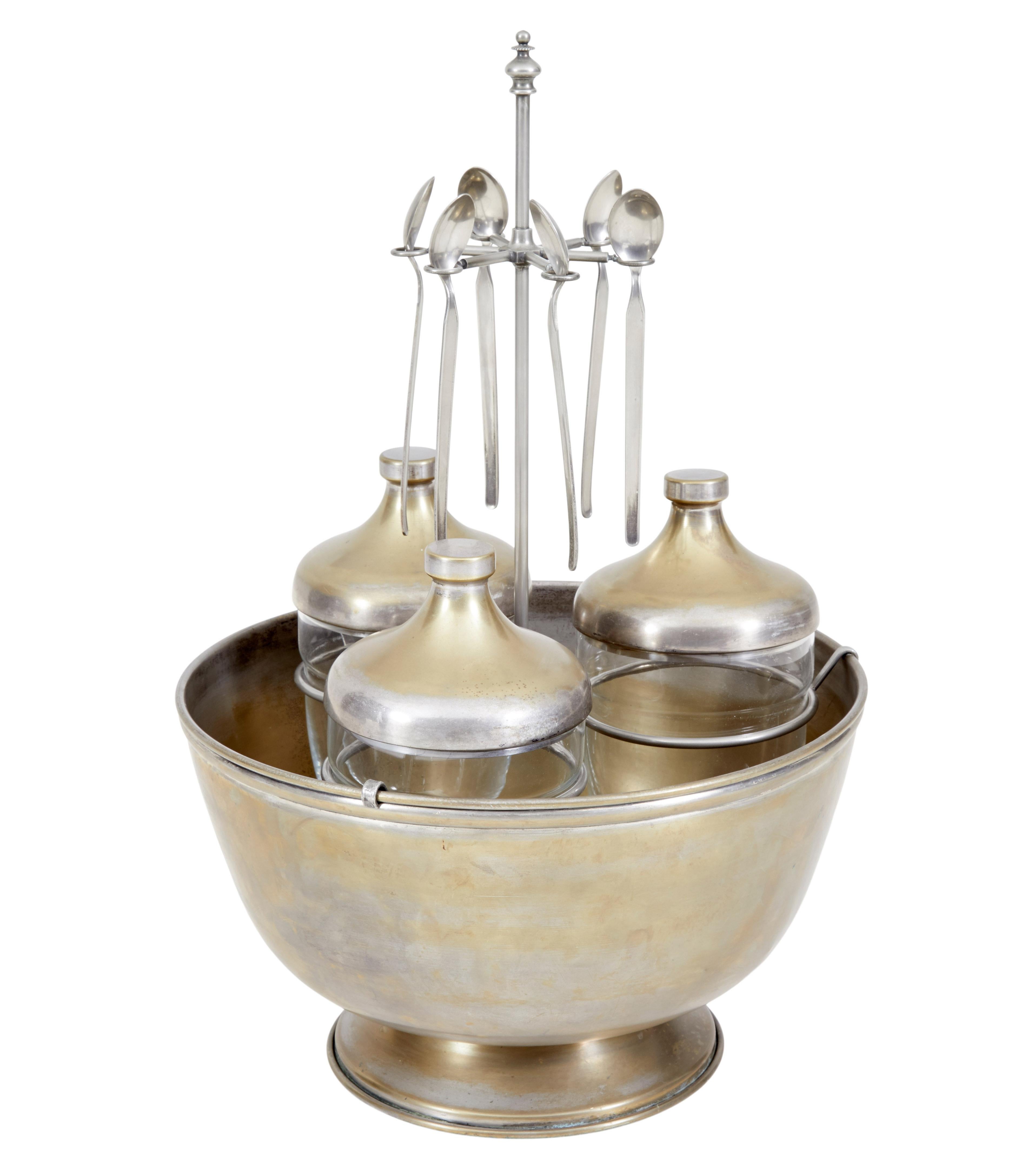 Interesting caviar set, circa 1920.

Comprising of four elements. Bowl, three jars with lids, holding rack and spoons.

Made from steel and gilded which has mostly worn away. The steel holder keeps the glass jars elevated and holds 6 spoons,