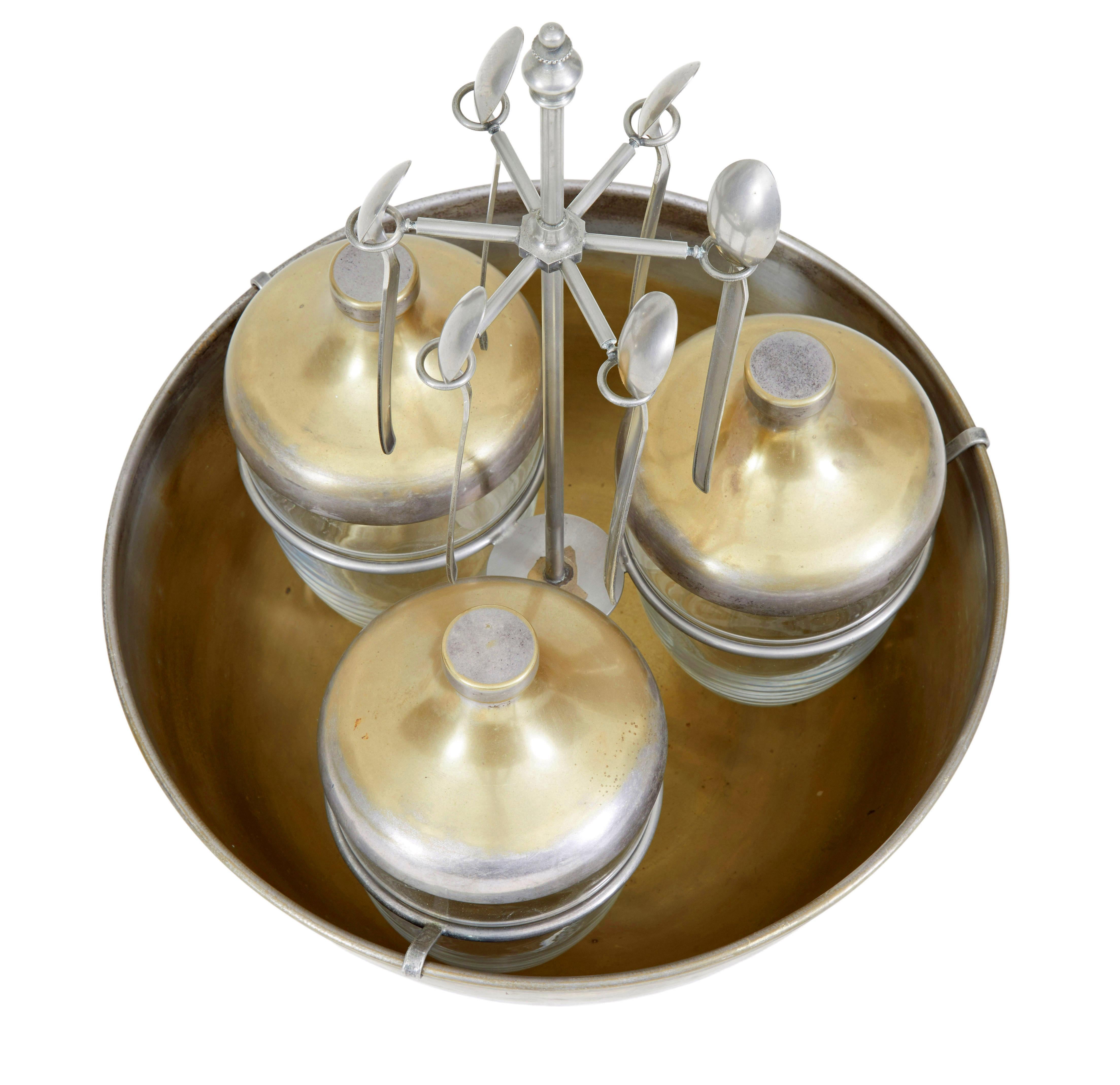 Interesting caviar set, circa 1920.

Comprising of four elements. Bowl, three jars with lids, holding rack and spoons.

Made from steel and gilded which has mostly worn away. The steel holder keeps the glass jars elevated and holds 6 spoons,